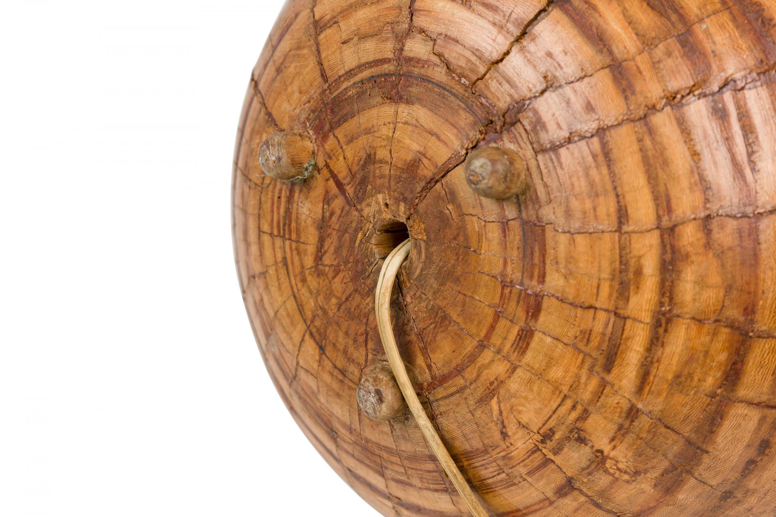 Amerikanische Tischlampe aus geschnitztem Palmenholz aus der Mitte des Jahrhunderts mit einem verlängerten Messingstiel, der in einen zylindrischen Pfosten mit zwei nicht funktionierenden Messingfassungen eingebettet ist. Der kugelförmige Körper