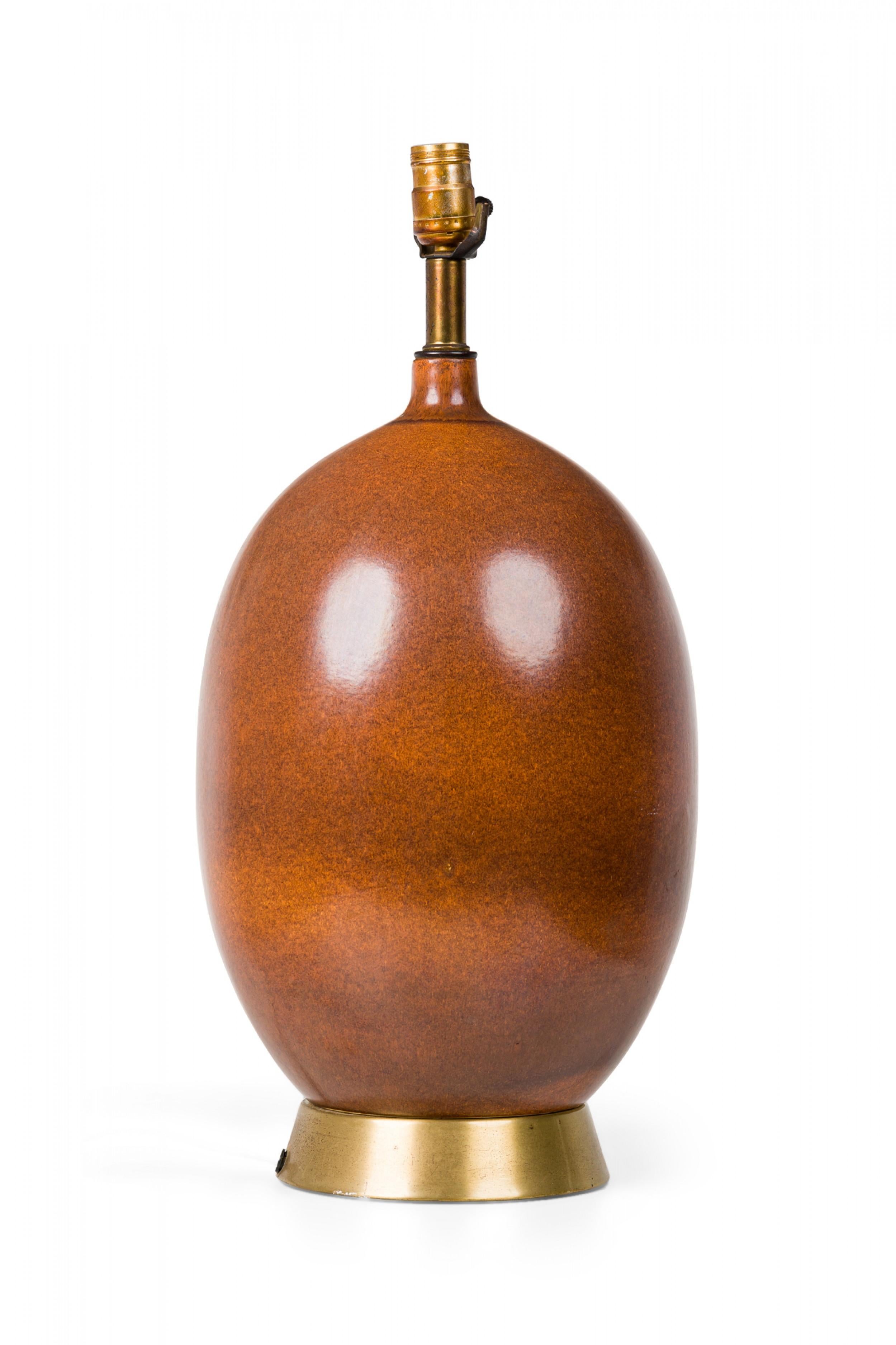 Mid-Century American ceramic table lamp in egg-like ovoid form with a pinched tapered neck extending to a fitted brass stem and functioning light switch socket, finished in a semi-gloss textured brown glaze with stippled gradations, mounted on a