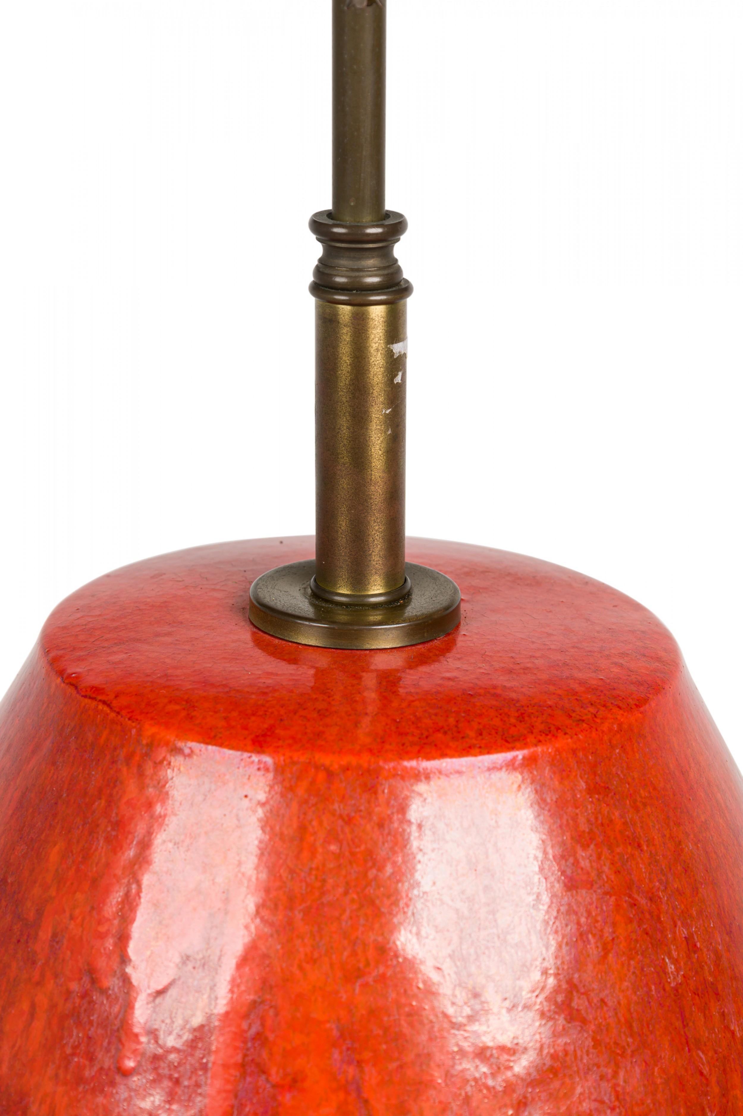 Mid-Century American ceramic table lamp in egg-like ovoid form with flattened top, an extended brass stem leading to a faux bamboo finial and two functioning light switch sockets with beaded pulls. The body is glazed in a textured burnt orange,