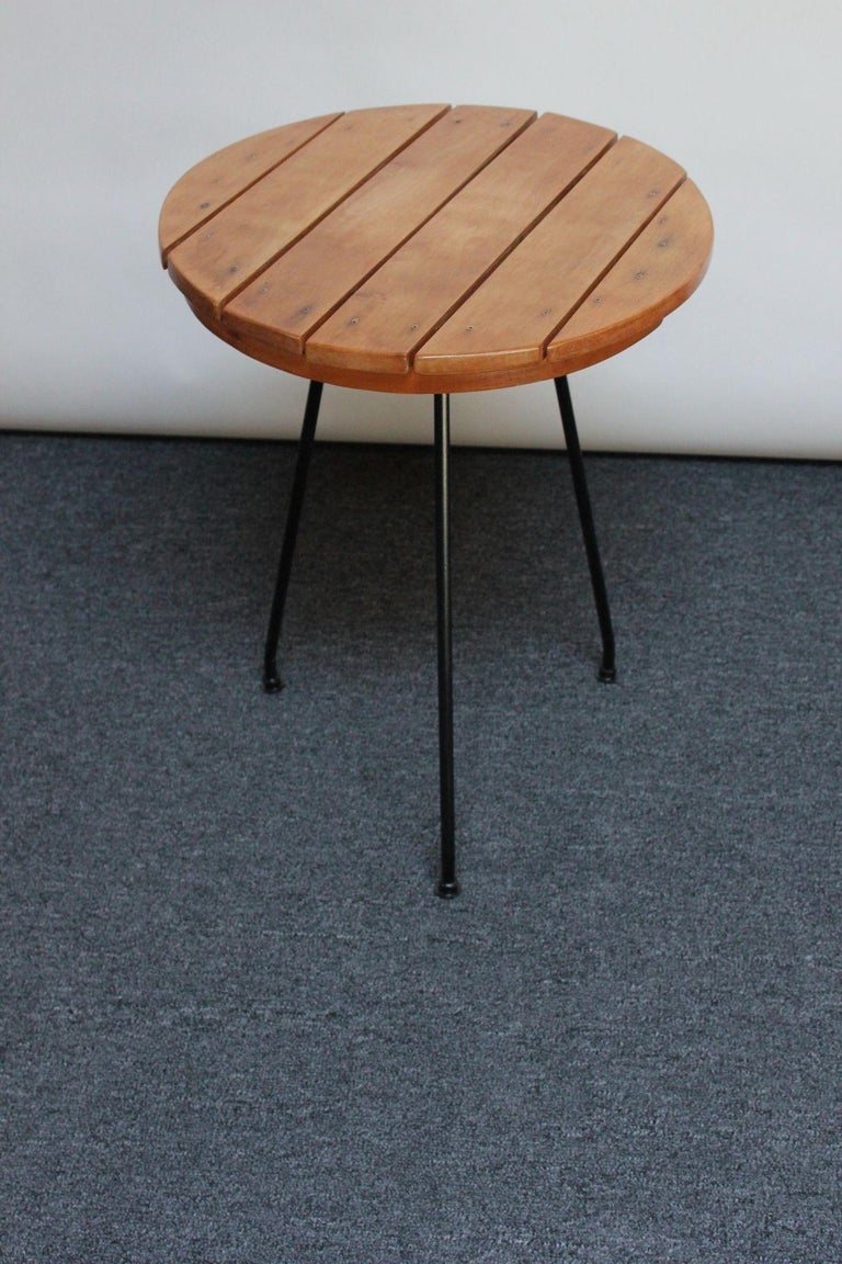 Arthur Umanoff for Shaver Howard accent / occasional table (ca. 1950s, USA). Composed of a round slatted birch top supported by three slightly splayed wrought iron legs retaining their original feet.
Birch has been conservatively refinished, and the