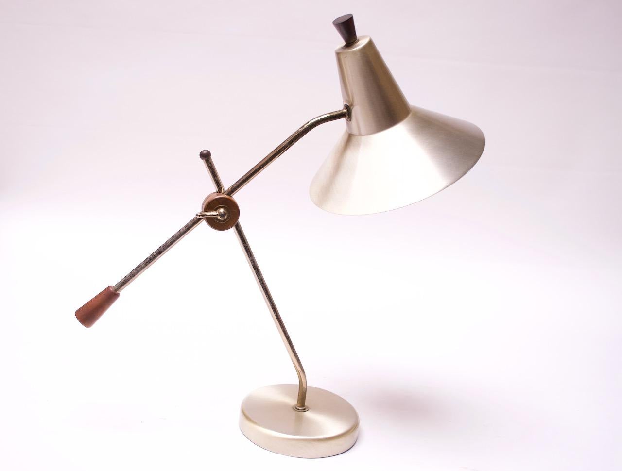 Elegant and highly functional 1950s American Modern adjustable table lamp in walnut and polished brass. The walnut and brass mechanism loosens the arm and allows for arm length and height adjustment (stem is fixed). The shade is additionally fully