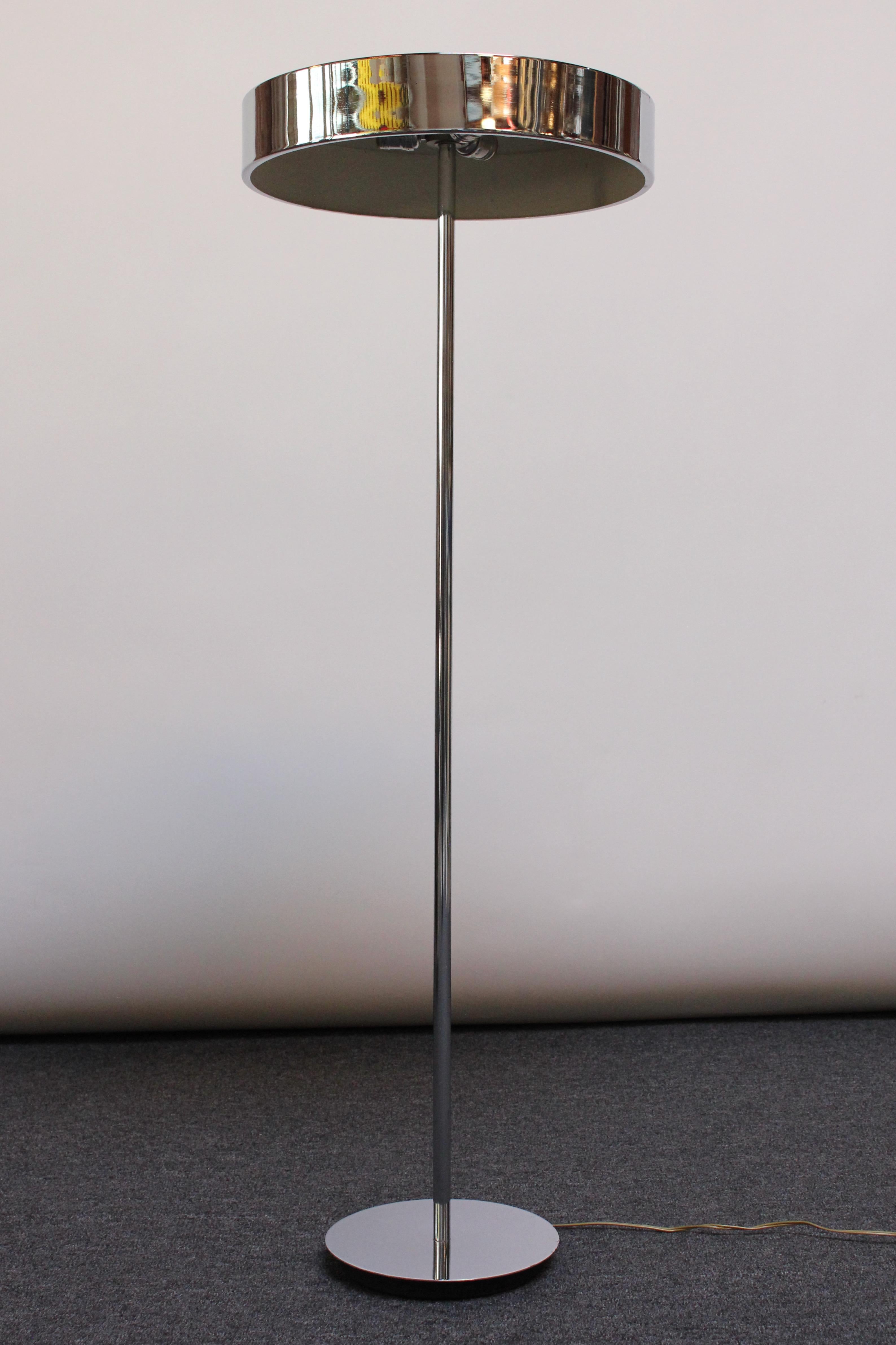 American Modern floor lamp consisting of a large, flat, cylindrical chrome shade supported by tubular chrome stem and circular base with a black weighted underside. This design is reminiscent of one by Ulrich Franzen, though the artist is unknown.