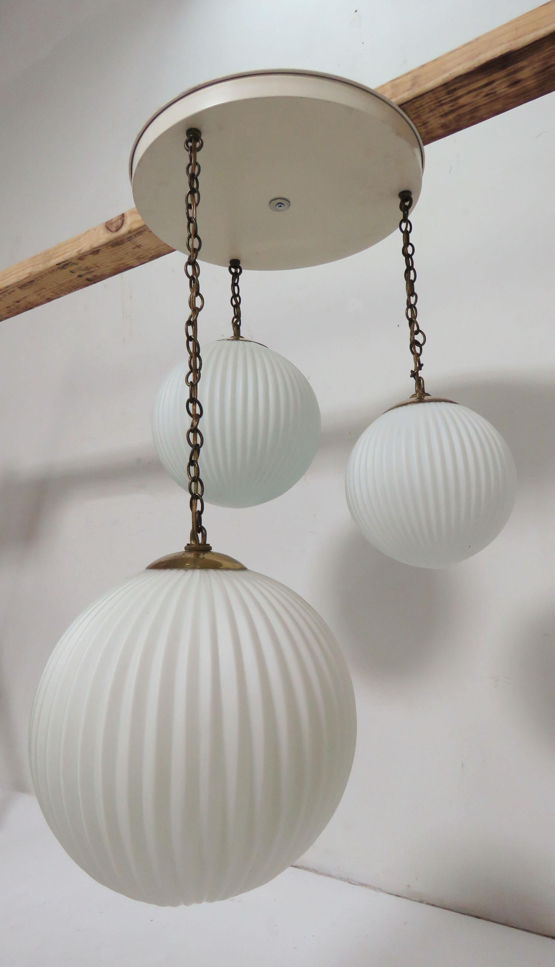 Mid-Century Modern pendant fixture of three ribbed glass globes, circa 1950s. 
Shades measure 12