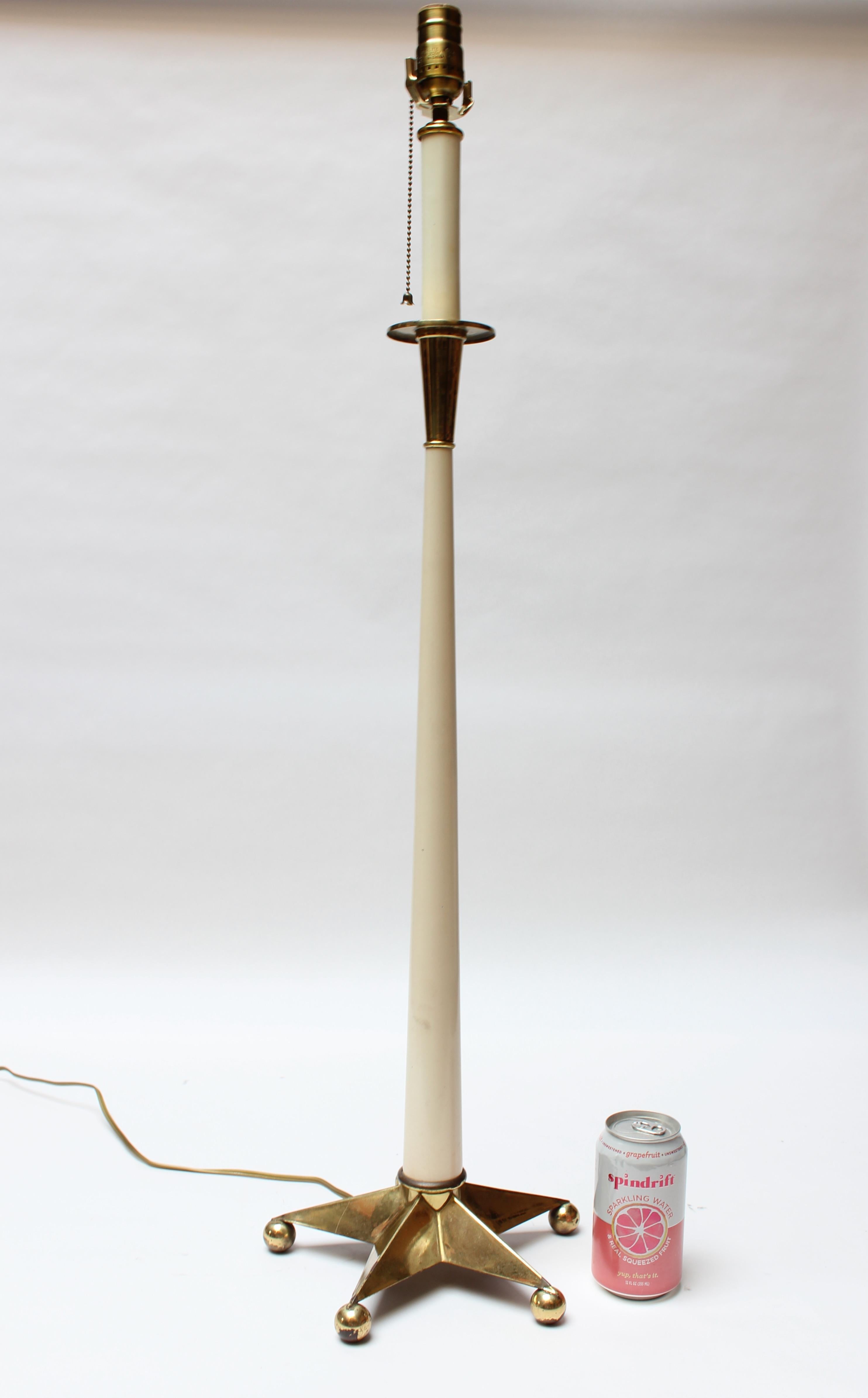 Mid-century table lamp composed of an-off white enameled metal stem with brass-plate star base and accents (ca. 1950s, USA).
Tall, statuesque form: (35.5