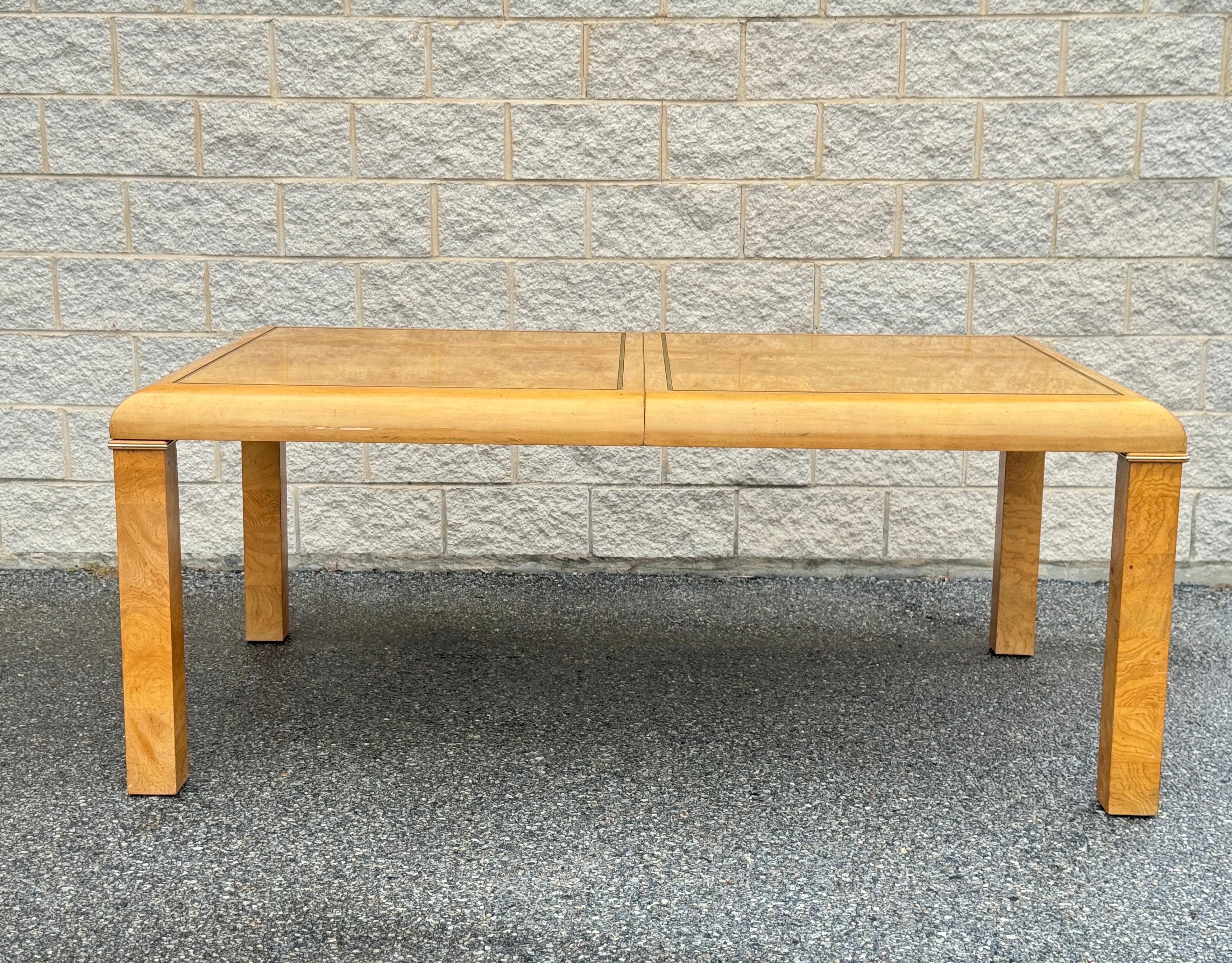 Cette table de salle à manger vintage d'American of Martinsville présente du bois ronceux dans un design Parsons classique. Il mesure 30 pouces de hauteur, 74 pouces de largeur et 44 pouces de profondeur, et s'étend jusqu'à 94 pouces avec la feuille