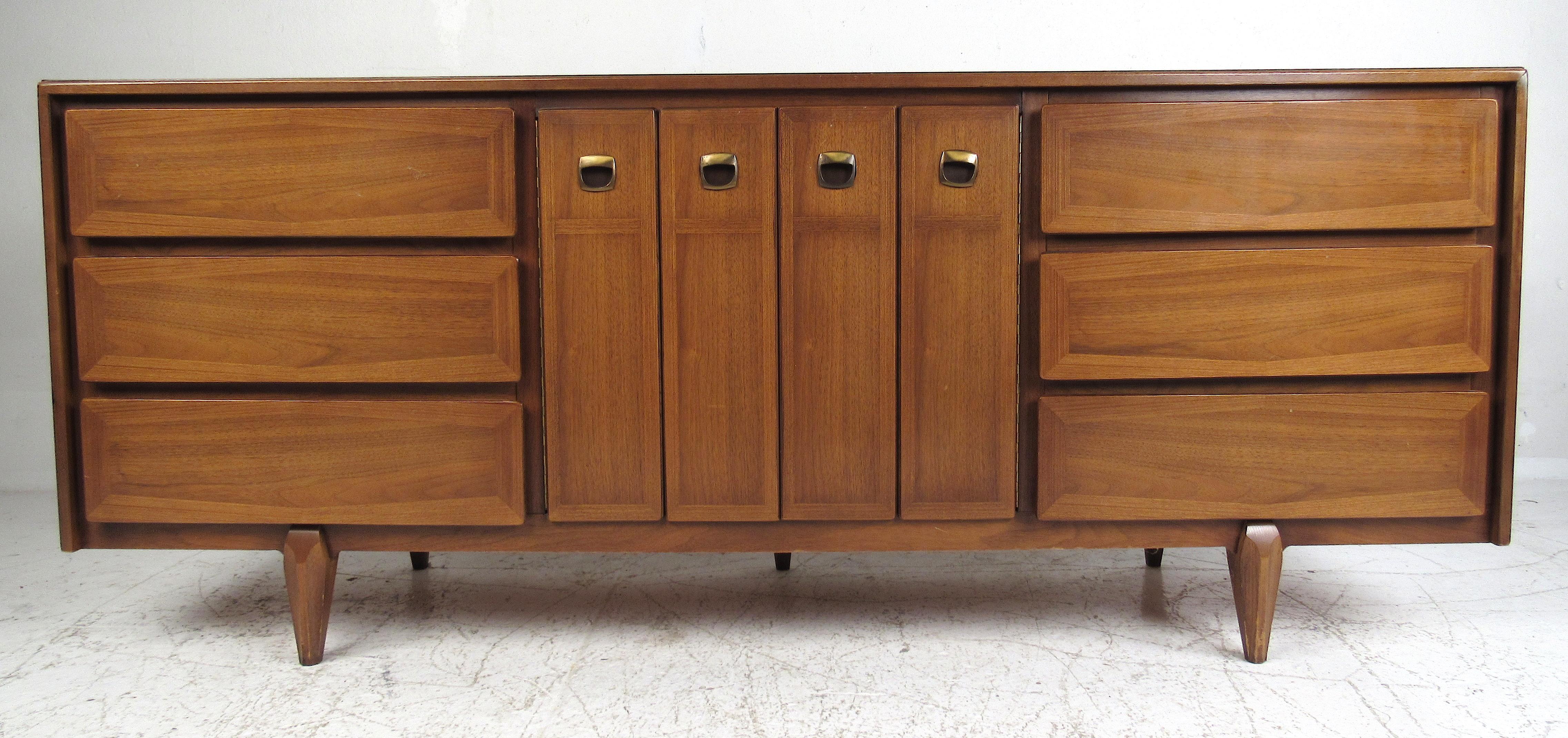 Beautiful matching set of two-drawer nightstands with a long nine drawer dresser by American of Martinsville. Providing plenty of storage, these well-designed cabinets feature sturdy tapered legs, walnut and oak construction, and banded drawer