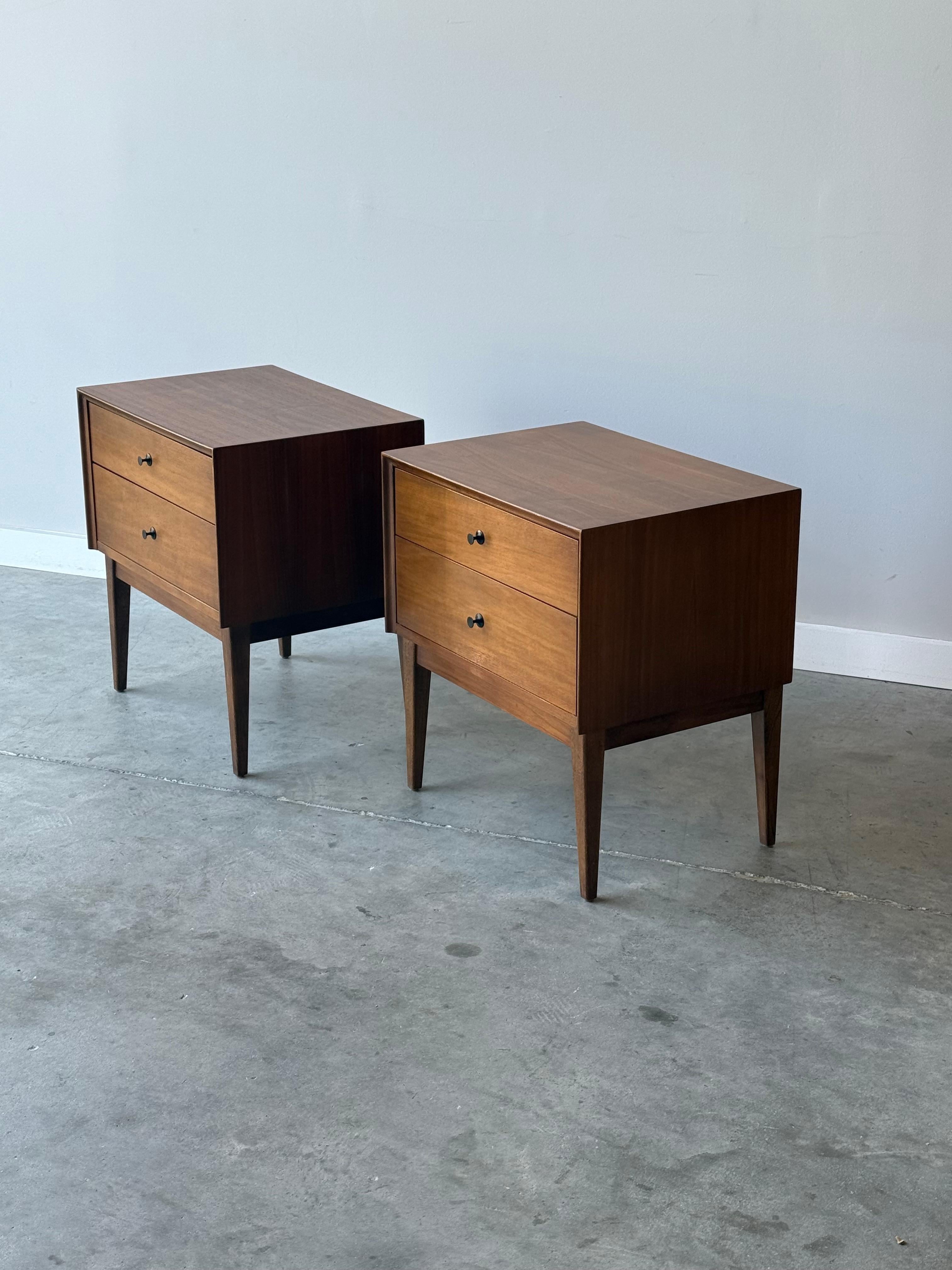 Mid-century pair of nightstands by American of Martinsville (AOM), made in the U.S. circa 1960s. This square shaped pair is made from walnut wood and features two drawers. Drawer pulls are original black circular metal pulls. The black contrasts