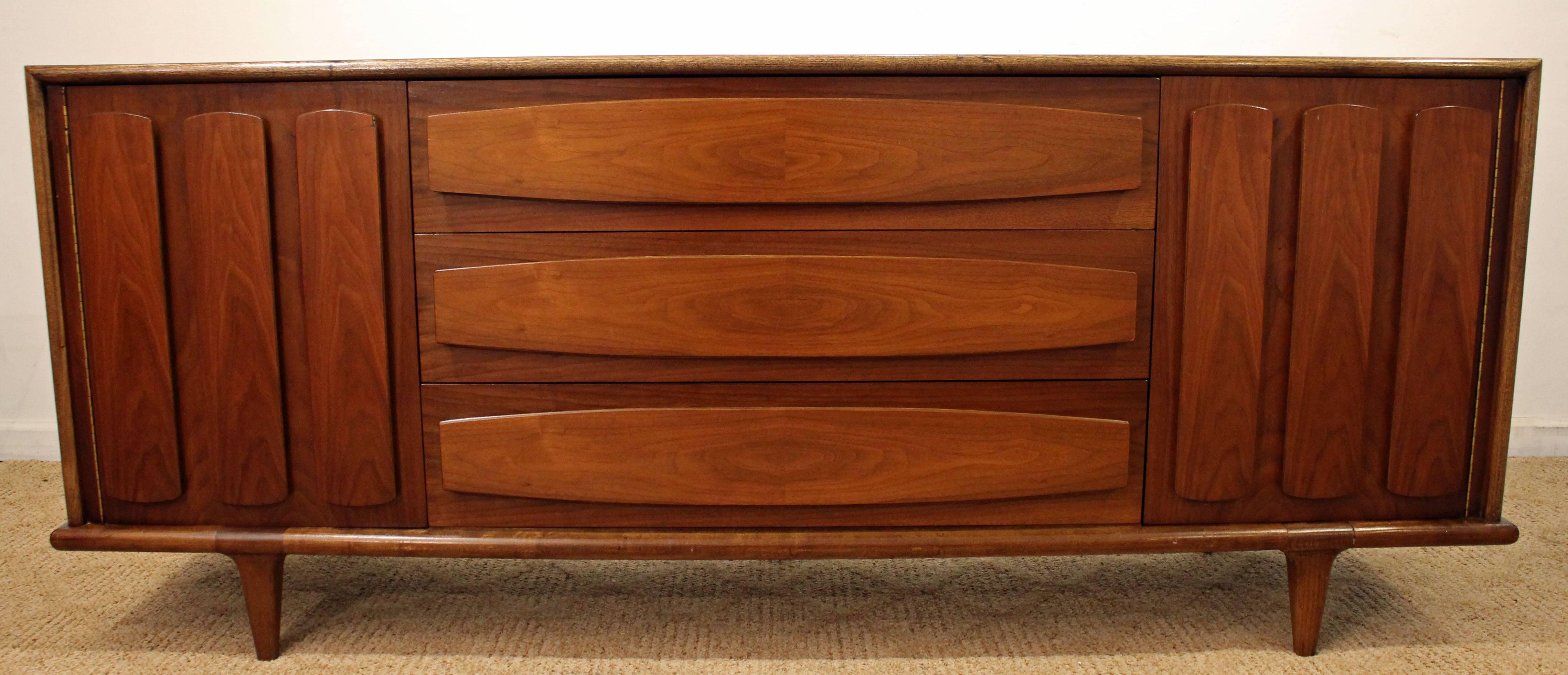 This piece is made of walnut with two doors on each side and nine dovetailed drawers. It is signed by American of Martinsville.