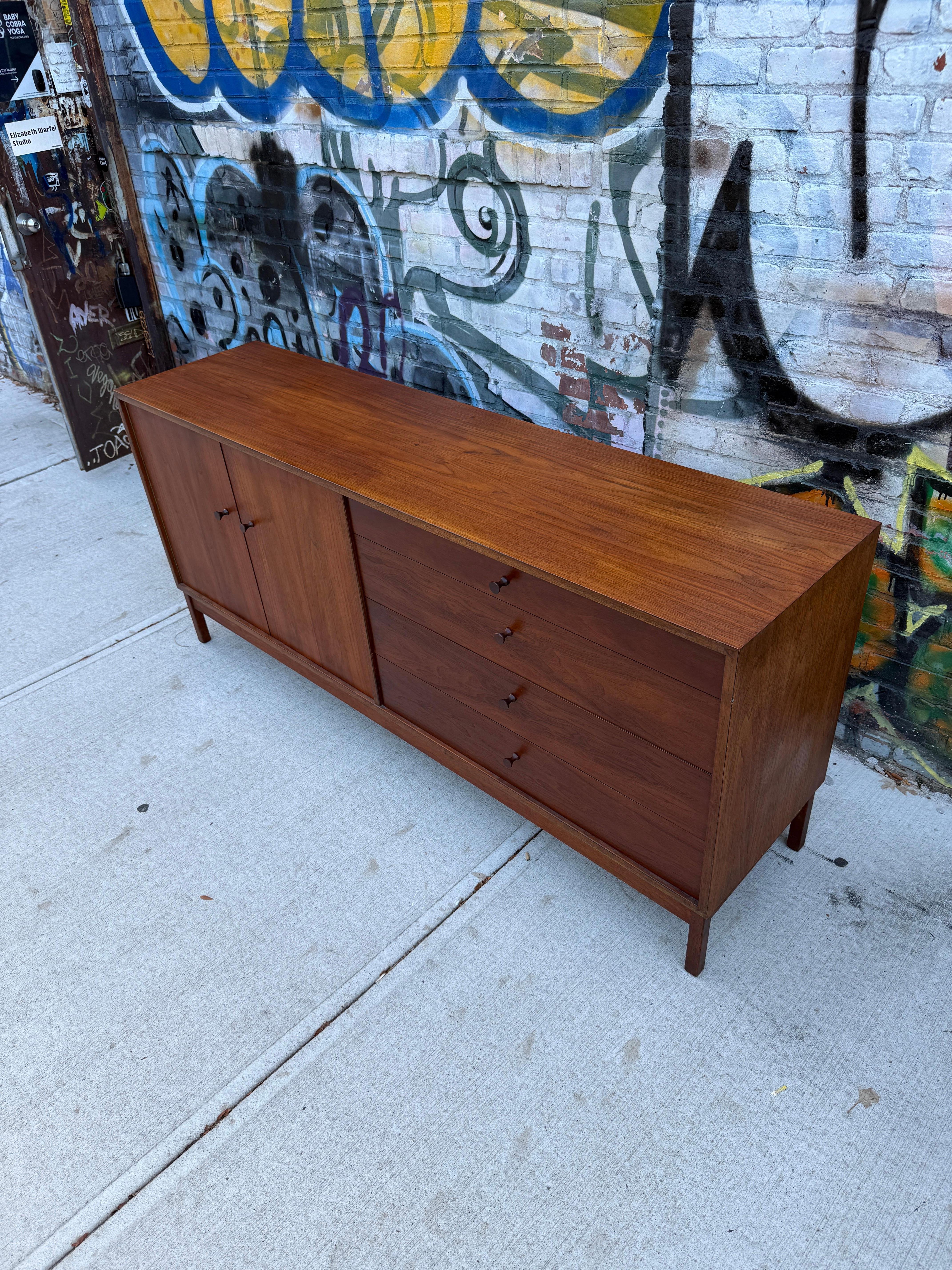 Beautiful American studio craft Mid-Century Modern long black walnut credenza with all solid carved walnut pull handles. The right side has (4) drawer and the left has 2 cabinet doors with an adjustable shelf behind the doors. Great design good