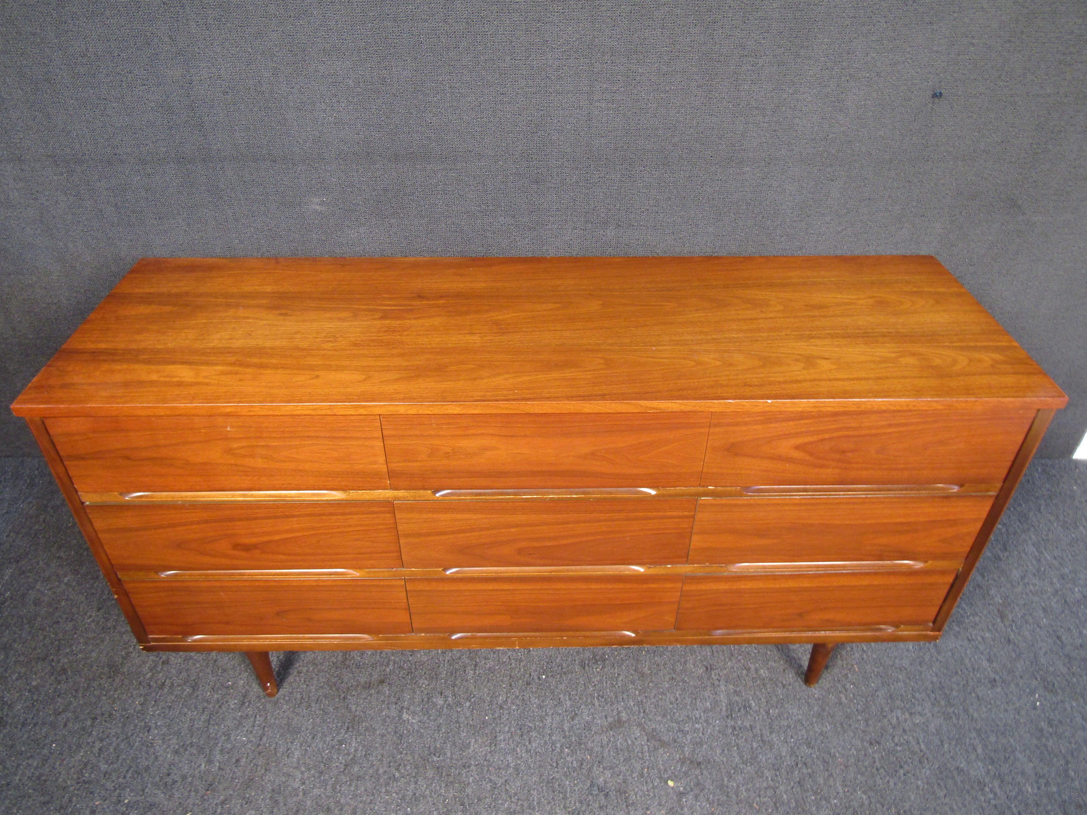 Mid-Century Modern walnut dresser with nine drawers. Features wood inset handles and tapered legs. If you are looking to furnish your bedroom with a vintage piece this would be a perfect addition.

Please confirm item location (NJ or NY).