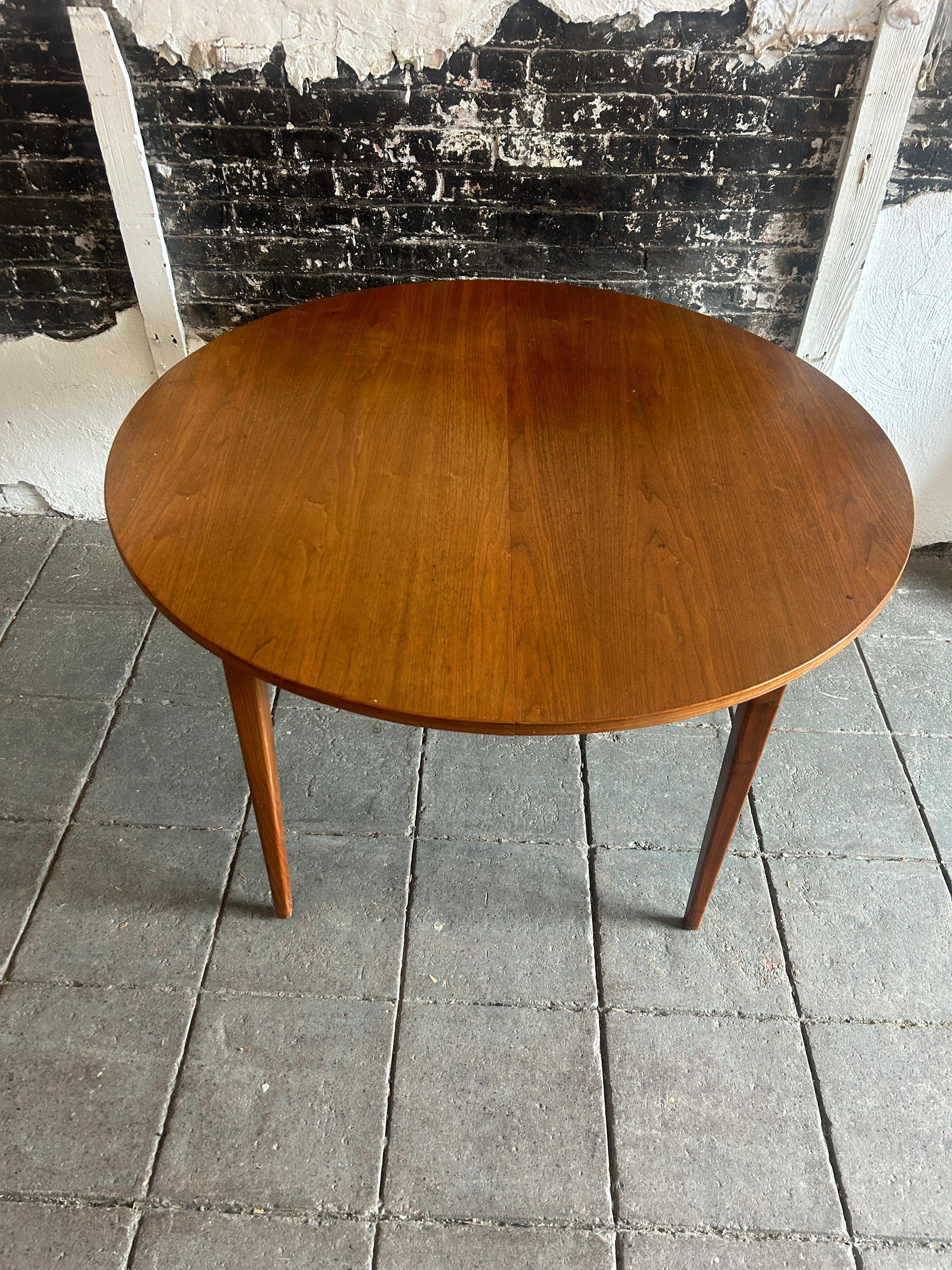 Mid century American walnut round dining table with 2 leaves. All wood table and extension glides circa 1960. The table is 45” in diameter with (2) 15” leaves. Table and leaves match very well. Great sturdy American mid century dining table. Legs