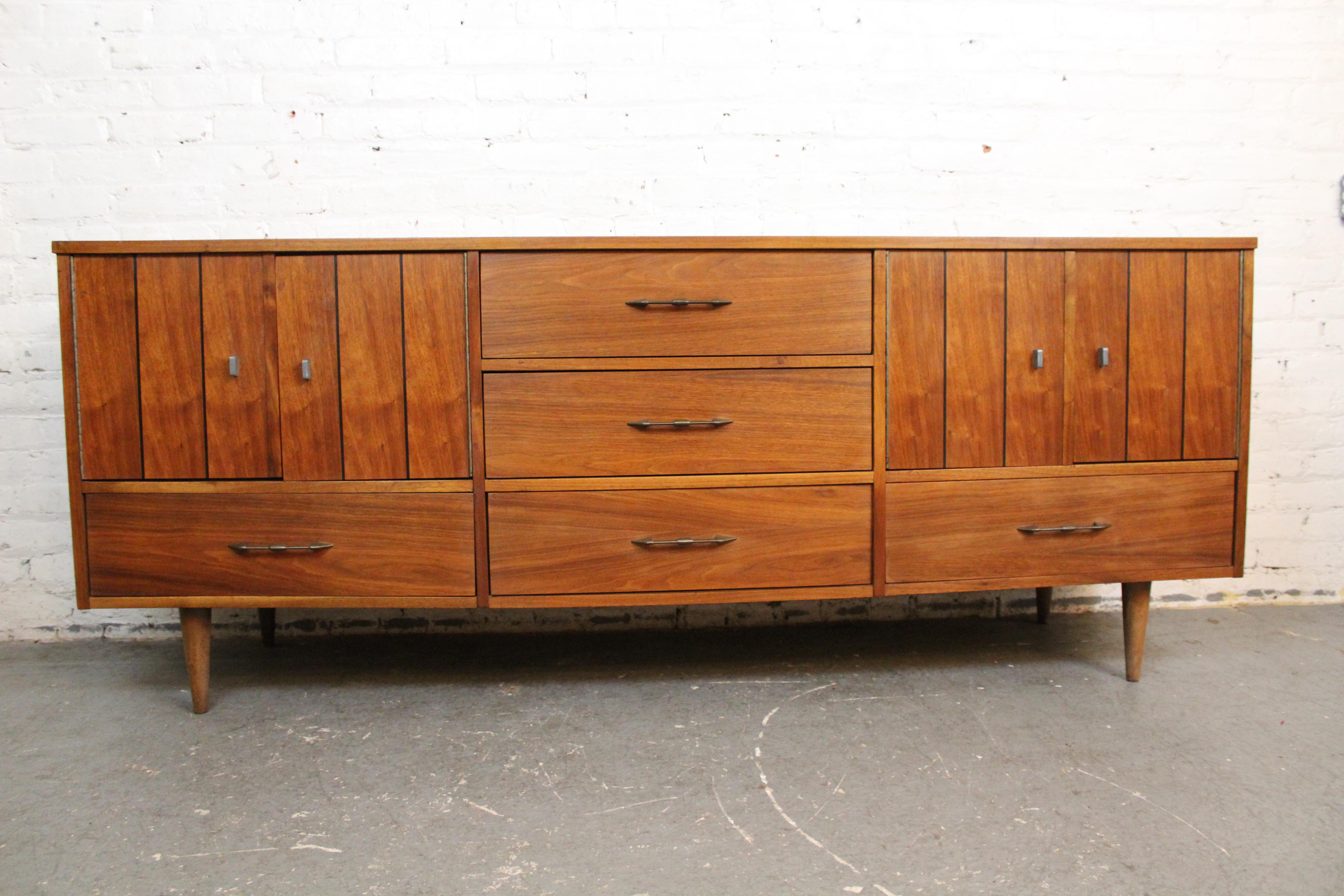Ajoutez de la gaieté à votre espace avec de véritables meubles modernes du milieu du siècle ! Ce magnifique buffet vintage en noyer a été conçu et fabriqué par la Young Manufacturing Company de Norwood, en Caroline du Nord, et affiche un style rétro