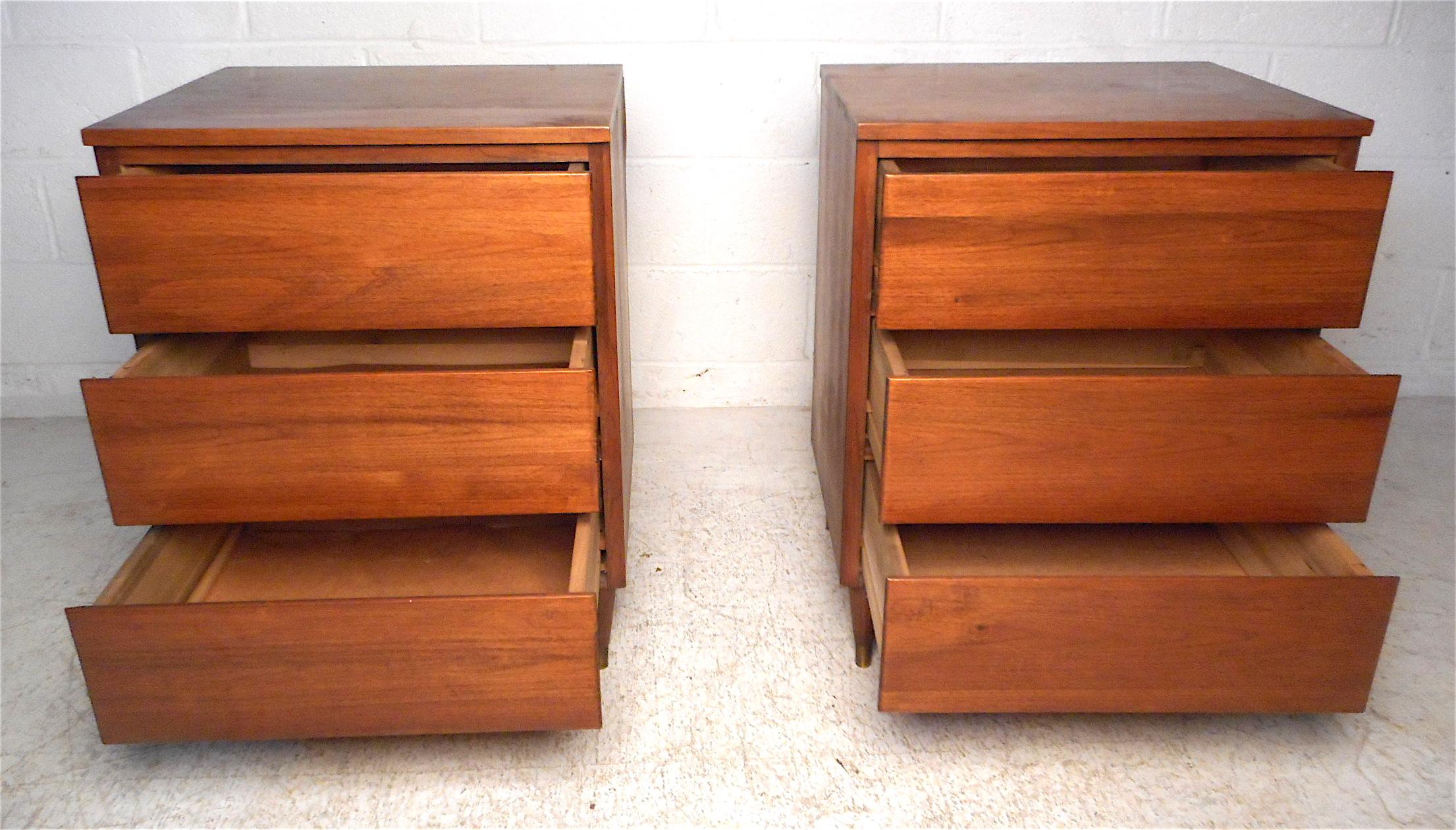 Mid-Century Modern style three drawer nightstands in walnut with brass capped tapered legs. Please confirm item location - NY or NJ.
  