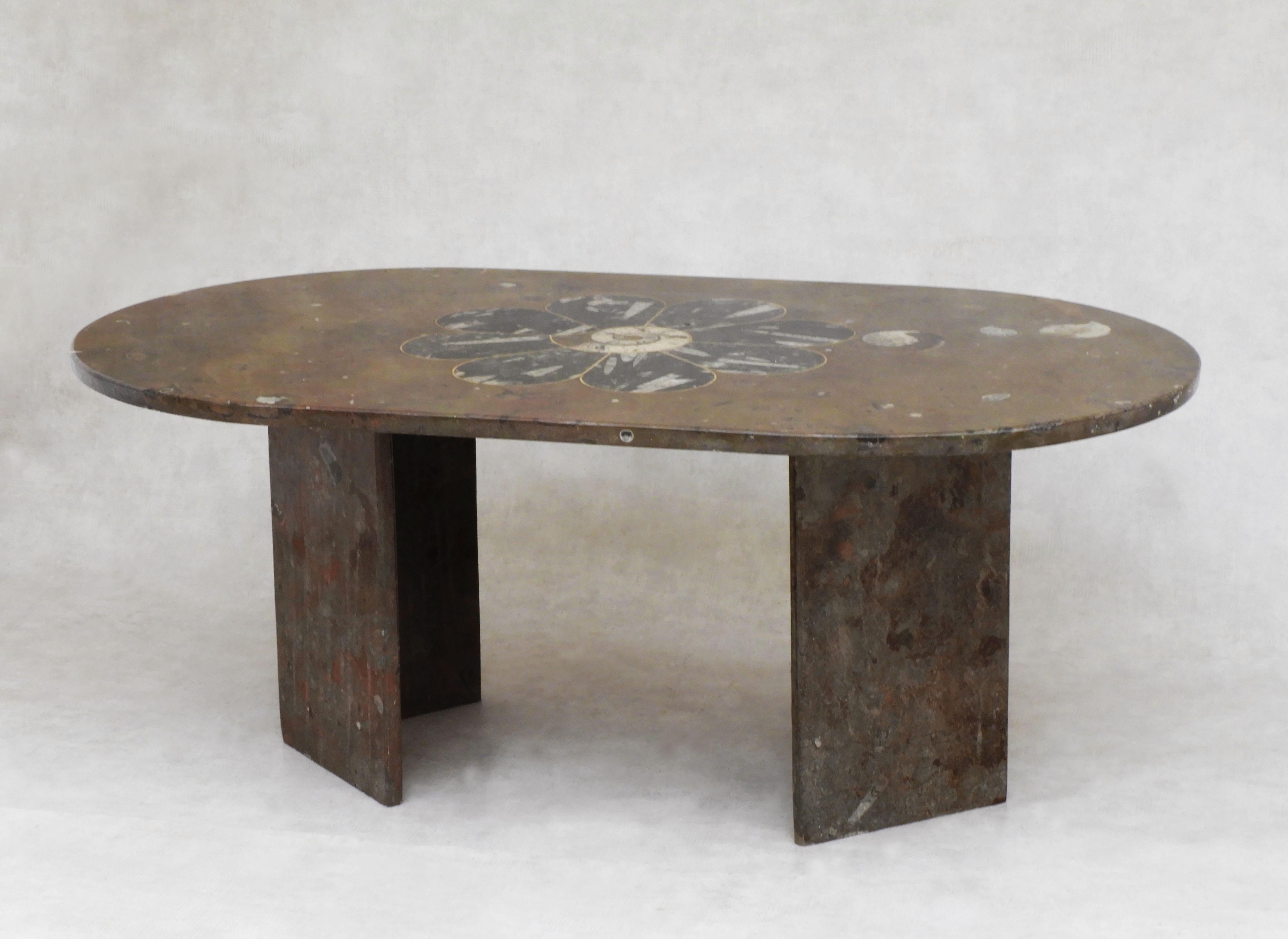 An eye-catching and unusual marble fossil coffee table from 1970s France.  Morrocan earth-toned marble embedded with ammonite and orthoceras fossils and accented with brass inlay in the form of an eight-petaled bloom. Commissioned in the 1970s, the