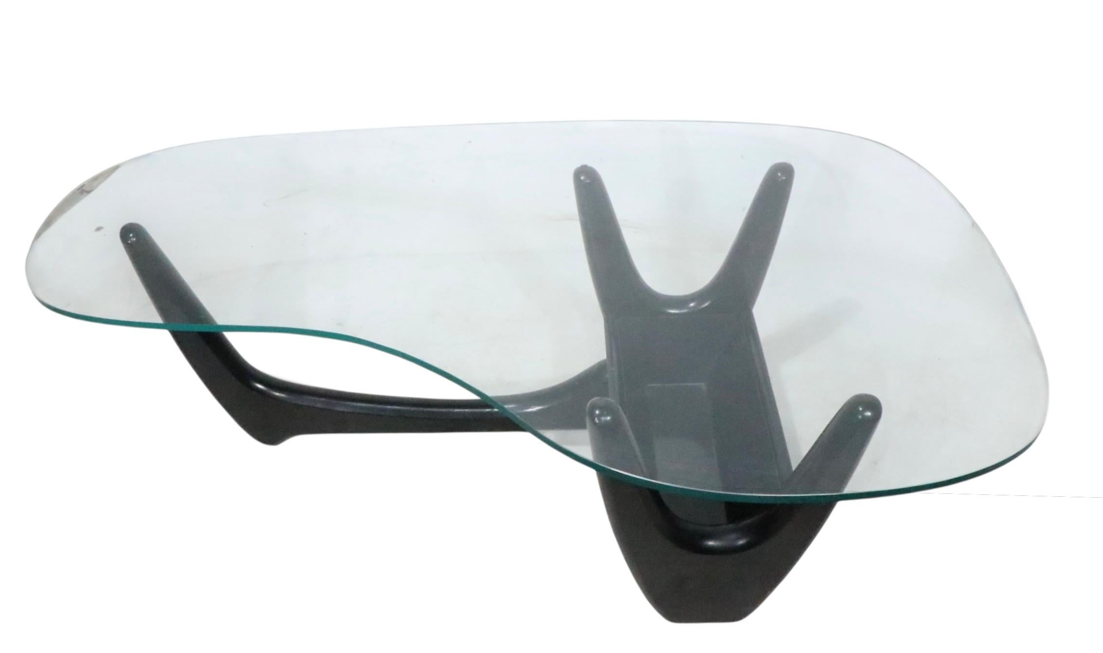 Table basse classique du milieu du siècle à plateau en verre de forme libre  sculptural  base laquée noire. La base comporte le cache-pot original doublé d'un insert, voir les images. Souvent attribuée à Adrian Pearsall, nous pensons qu'elle a été