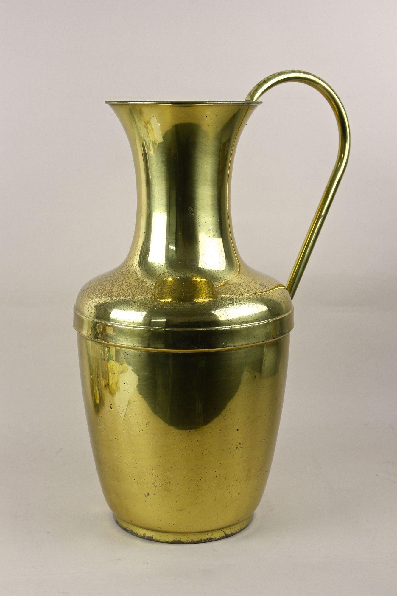 Fantastico vaso in ottone ad anfora di grandi dimensioni della metà del secolo scorso con manico, risalente agli anni 1940/50 in Austria. Questo vaso decorativo in ottone ha un'altezza di 21,2 pollici e colpisce per la sua forma elegante e il manico