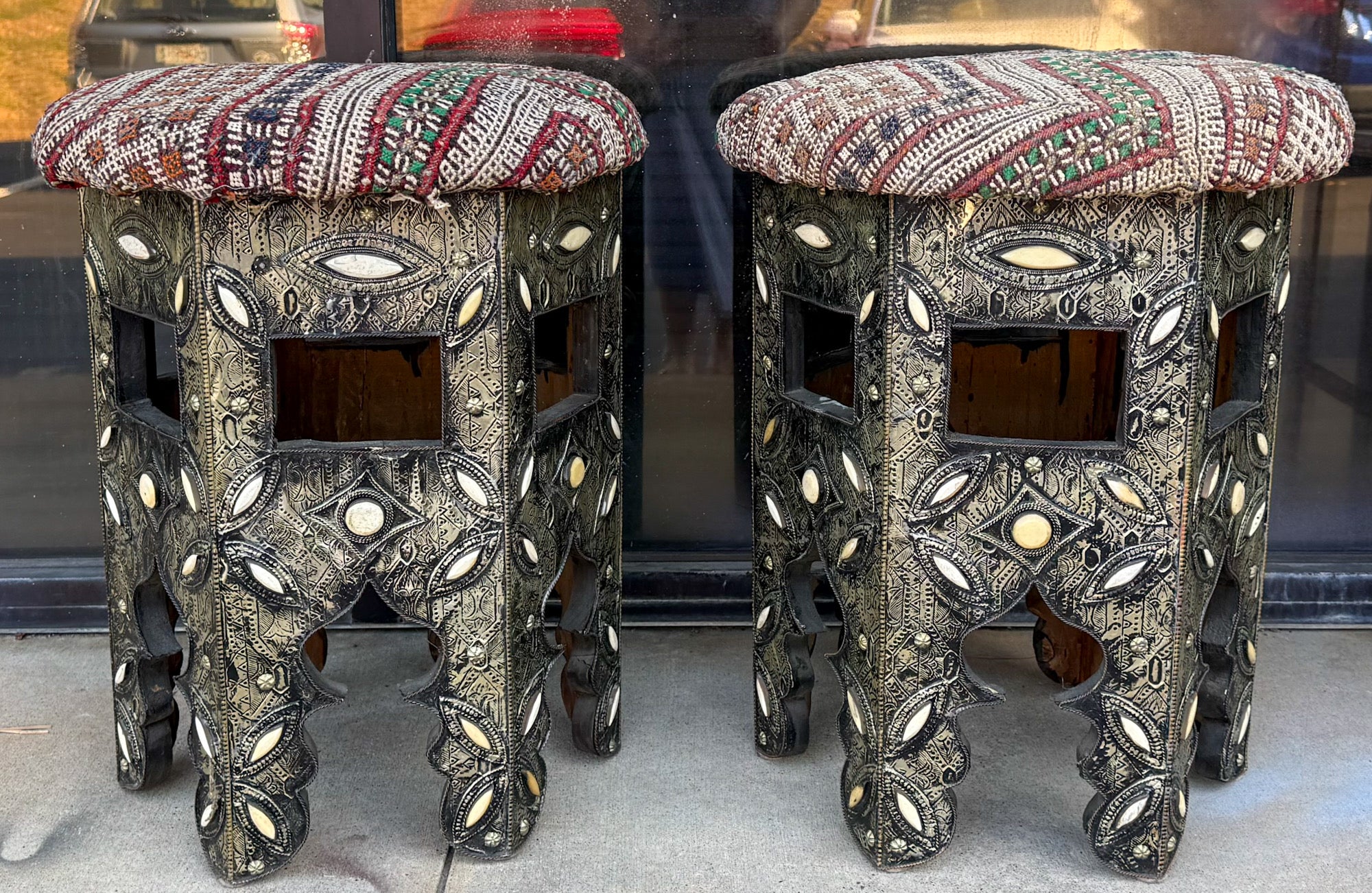 Il s'agit d'une paire de tables d'appoint ou de tabourets en marqueterie anglo-indienne. La tapisserie d'ameublement est un textile tissé et est vintage sans trous. Le corps est en bois enveloppé d'un métal gaufré complexe avec des incrustations
