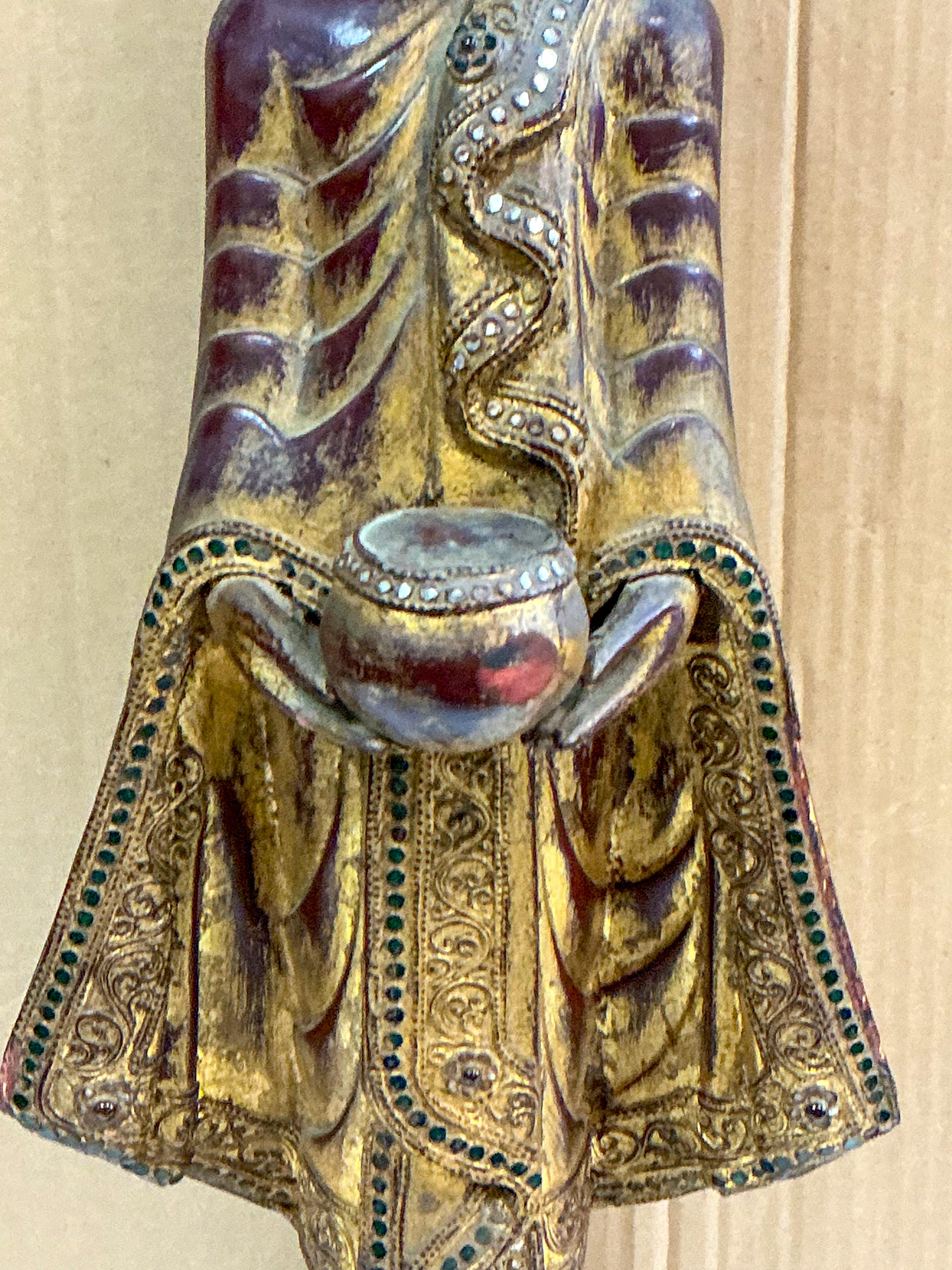 This is a mid-century carved giltwood Buddha figurine or statue. It is depicted standing on an ebonized 4 inch square base. It is a religious figure depicted in the standing position with an offering. It is unmarked.