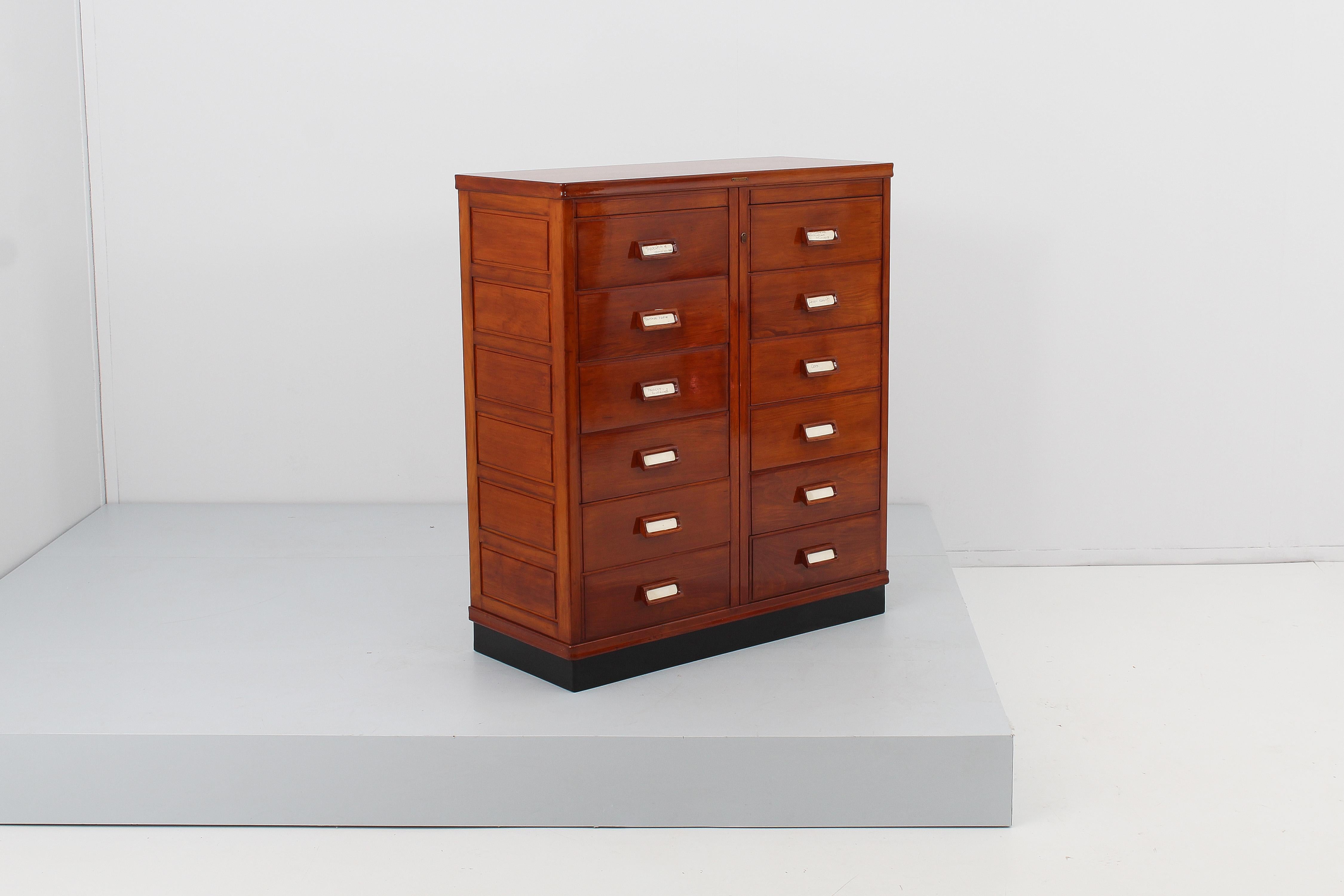 Huge and prestigious filing cabinet with twelve capacious drawers, with flap front part to facilitate the consultation of the documents inside. Each drawer has a compartment for the label. The recently restored piece of furniture has the original