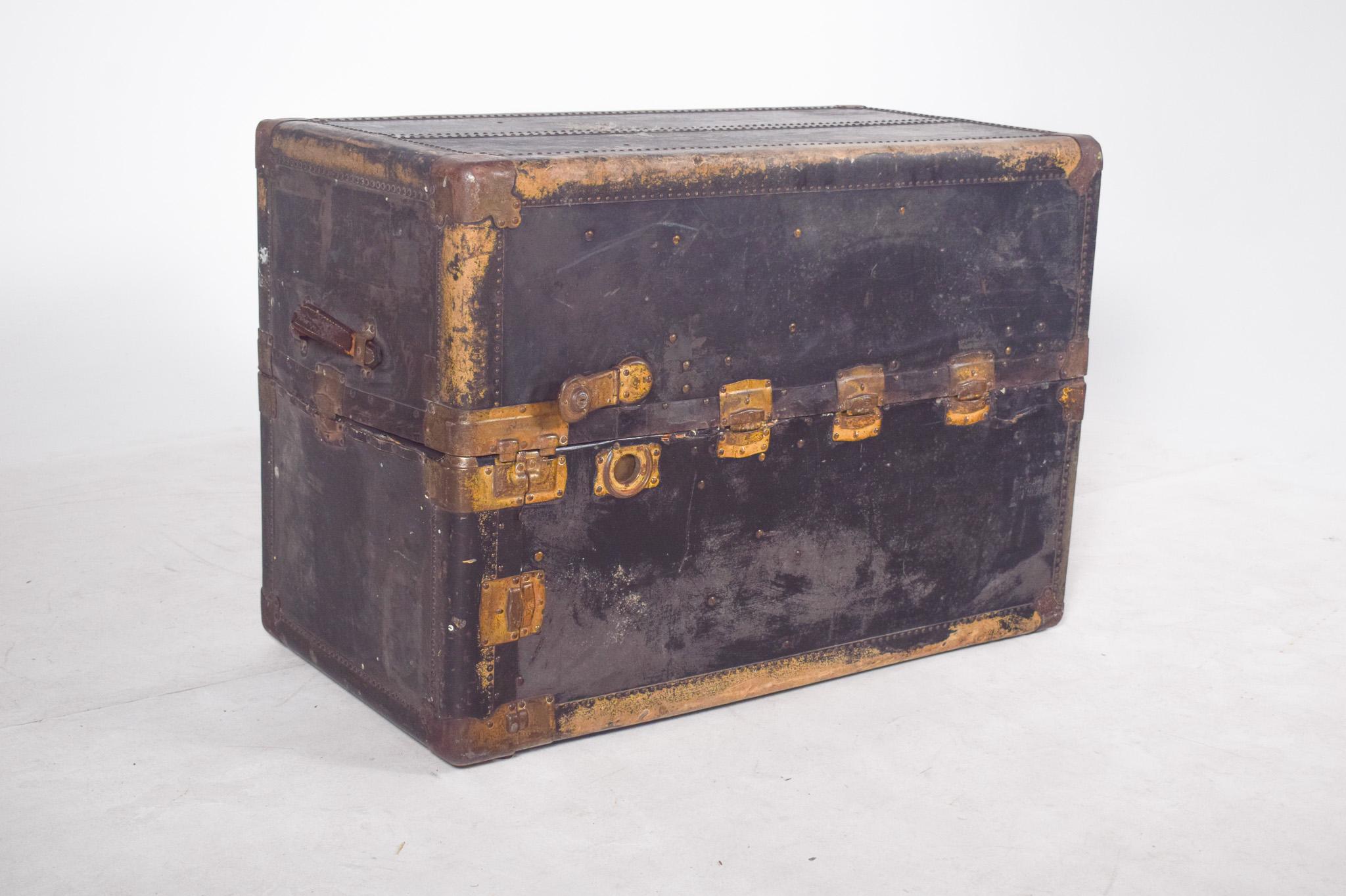Borsa da viaggio antica, rivestita in pelle nera. Di grandi dimensioni, rivestito in pelle nera, con una struttura in legno rinforzata da staffe angolari e accessori metallici, visibilmente ossidati dal tempo. Questo pezzo, un tempo utilizzato per