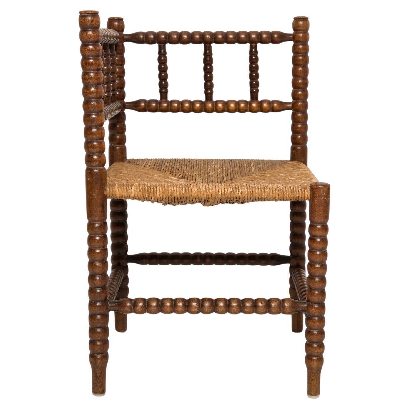 Fina silla esquinera de estilo provincial francés en roble teñido con asiento de caña hecho a mano. Patas clásicas torneadas de bolillos y en general en buen estado vintage. Fabricado en el siglo XIX.  Preciosa silla hecha a mano que complementará