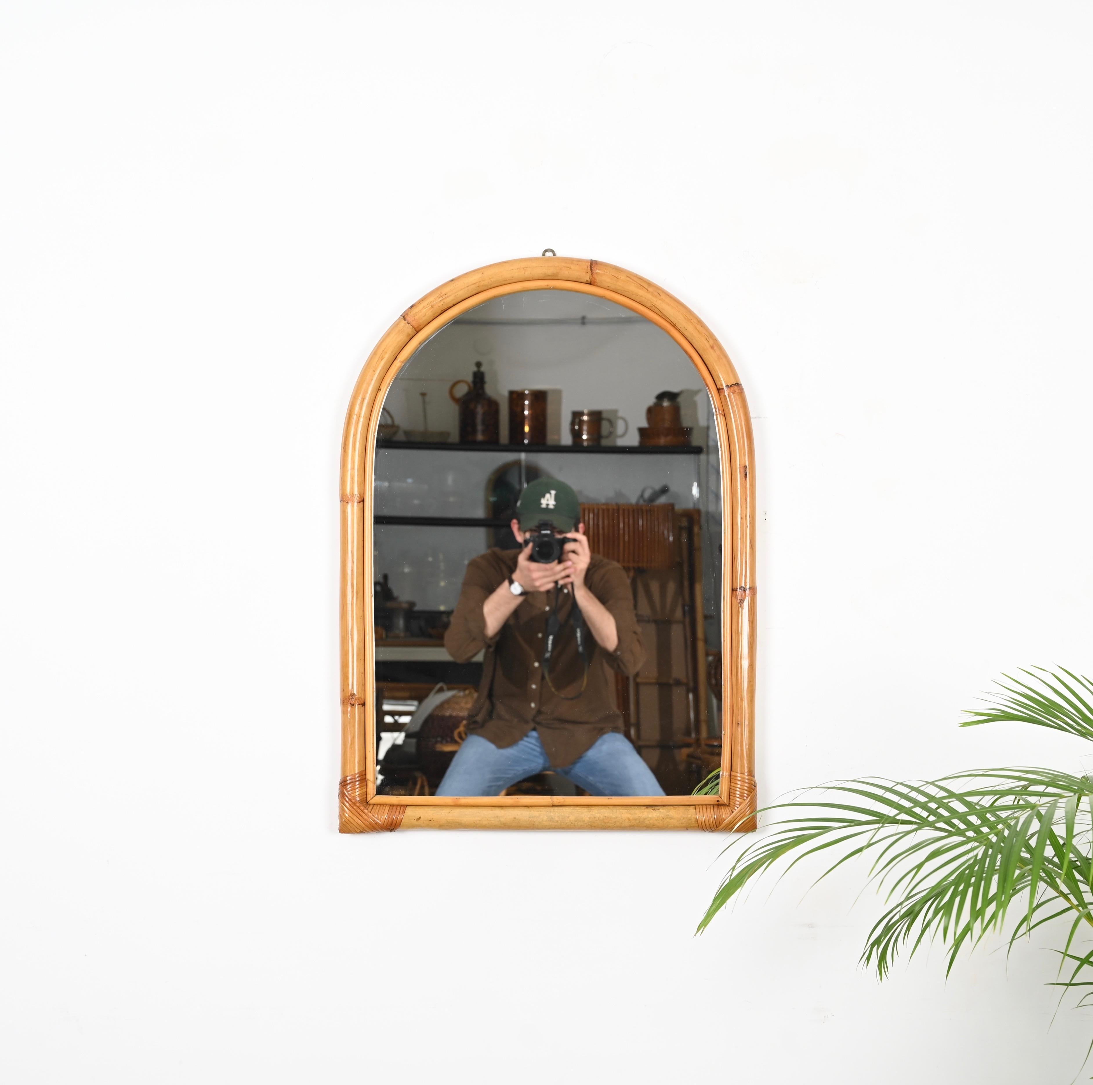 Gorgeous Mid-Century arched mirror with double bamboo cane frame. This lovely item was produced in Italy in the 1970s.

The way the two-round bamboo canes curve together creating a perfect arch and integrate the glass mirror is superb and conveys