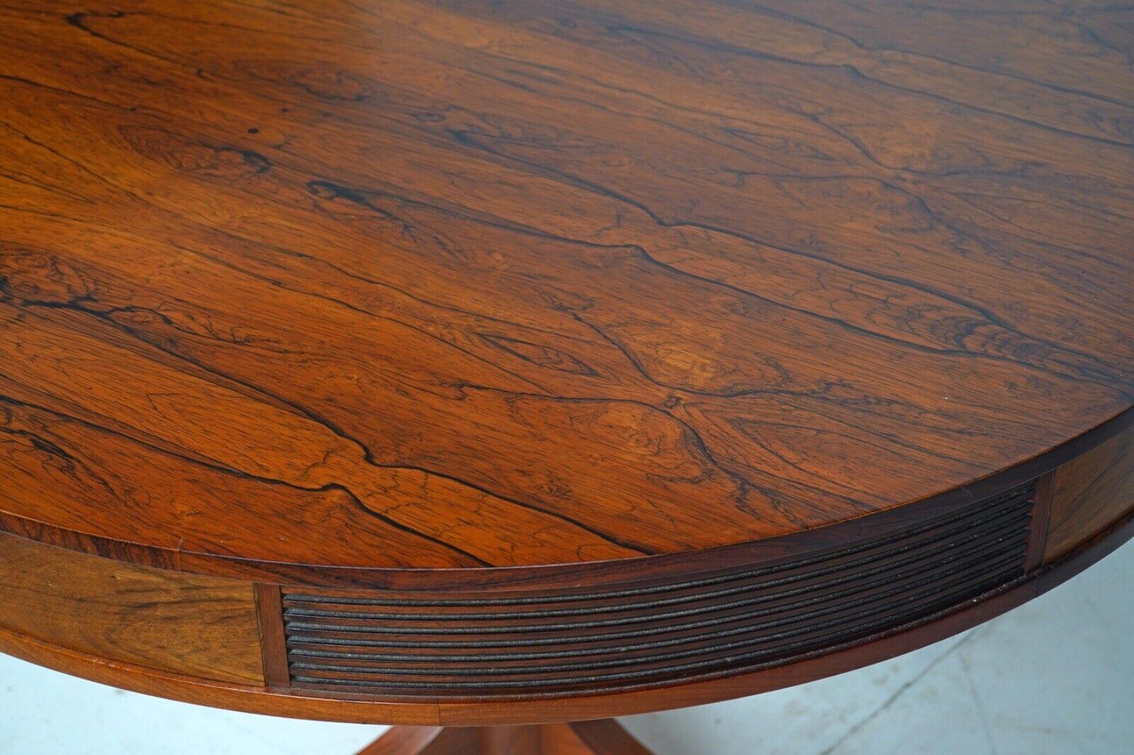 A beautiful rosewood 'Bridgeford' drum table and 8 Rosewood dining chairs.

Designed by Robert Heritage for Archie Shine, 1960s, London. 

Tripod pedestal design with four drawers with recessed handles and reeded detail panels between drawers.