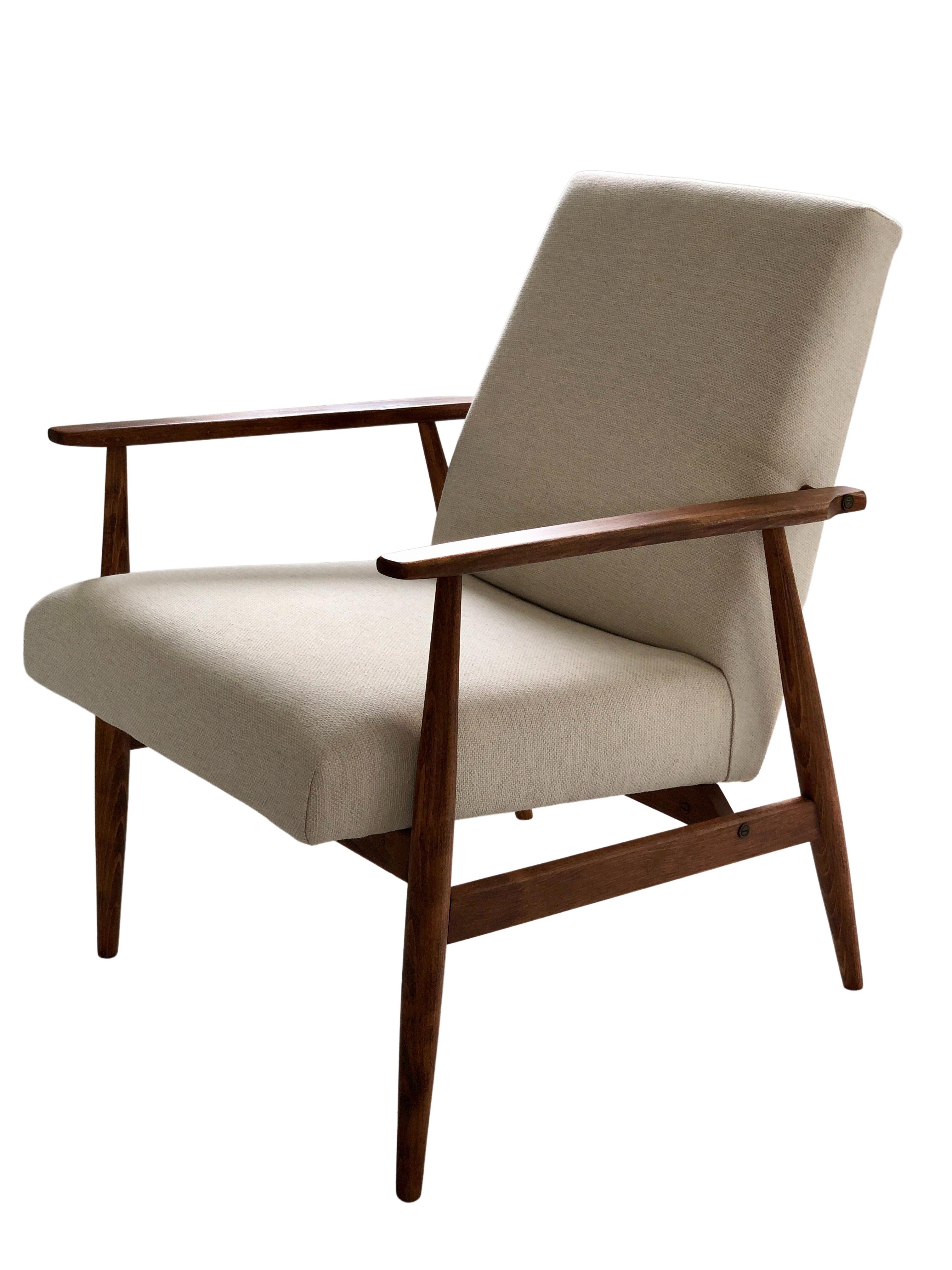 Le fauteuil conçu par Henryk Lis. La structure est en bois de hêtre de couleur noyer chaud, finie avec un vernis satiné semi-mat. Le revêtement est un tissu de coton naturel de haute qualité et de poids élevé, de couleur beige. Le fauteuil a été