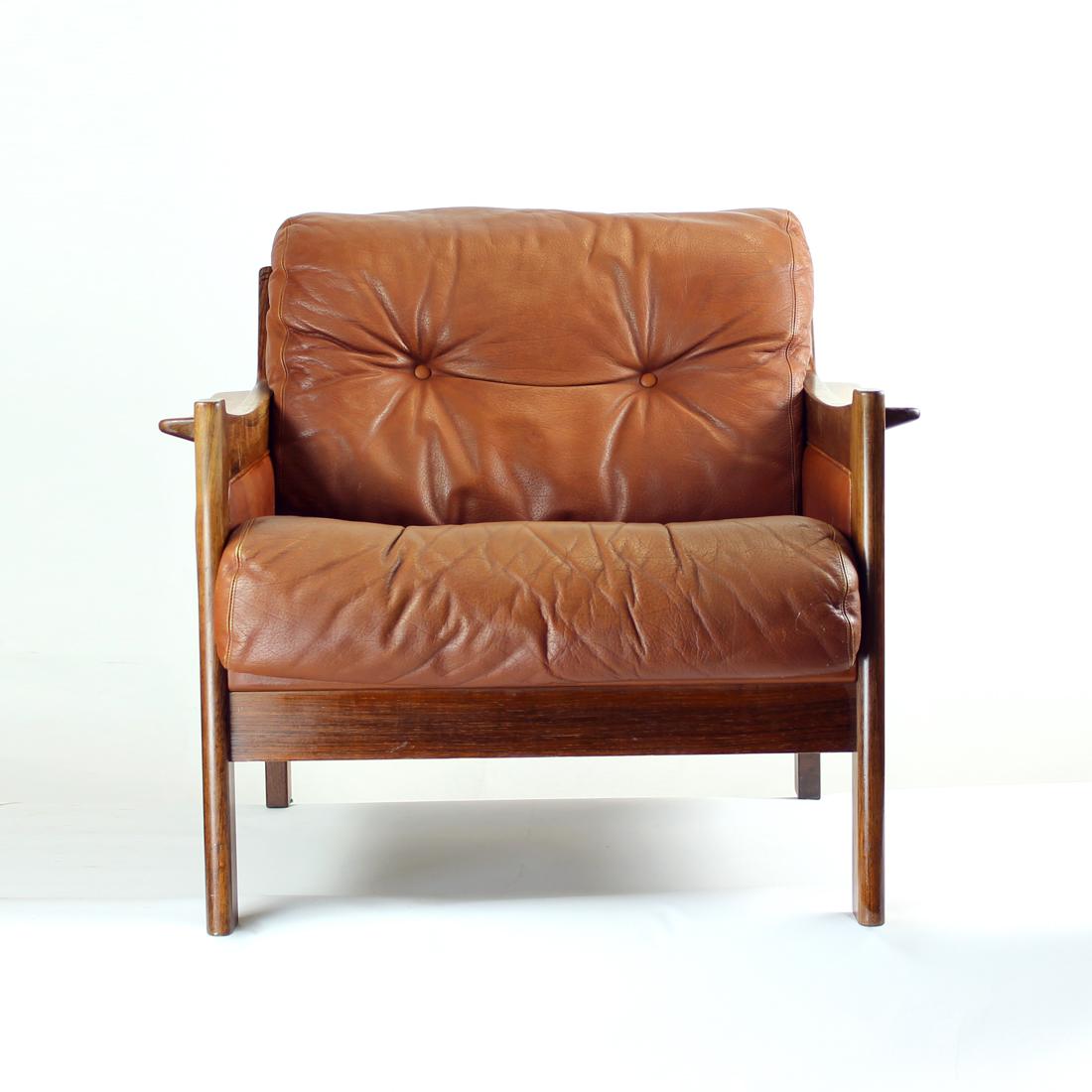 Beautiful armchair or lounge chair produced in 1970s. The frame is a great piece of wood work with some amazing details. The wood is solid rosewood with amazing pattern. The seat and backrest is finished with a cushion in cognac leather. Excellent