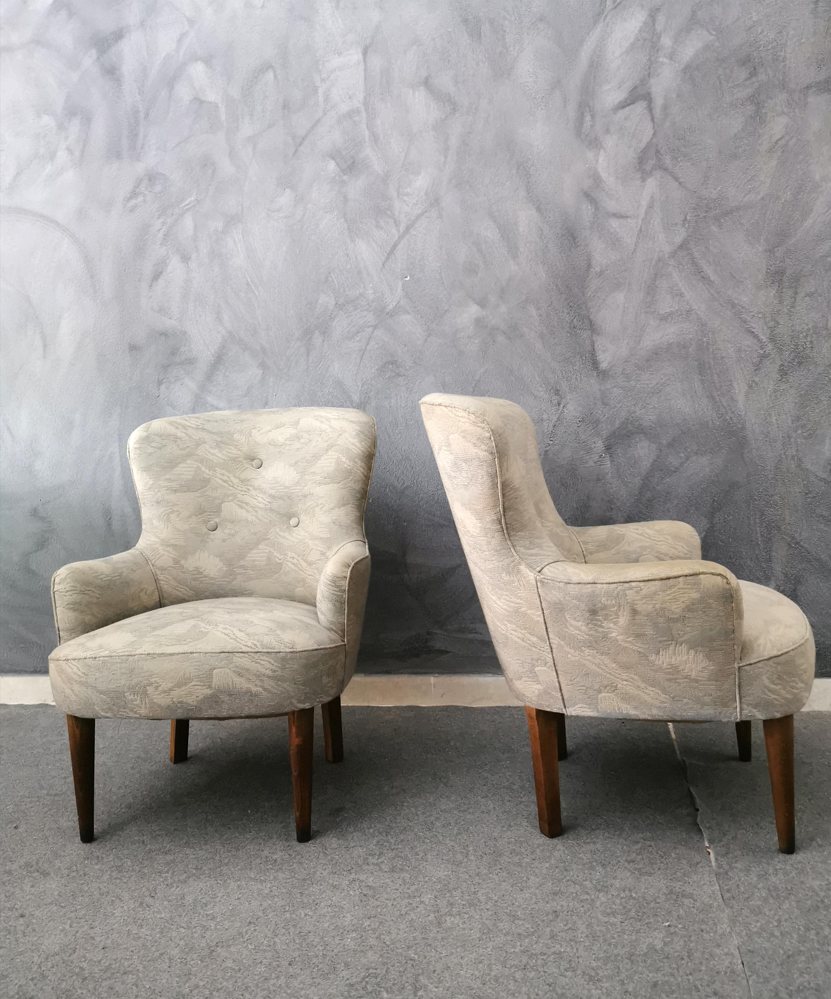 Set of 2 small armchairs covered in striped fabric depicting a mountain landscape. The set has the particularity of having the 2 front feet that end in a round shape, while the rear ones in a square shape, all in wood. Italian production from the