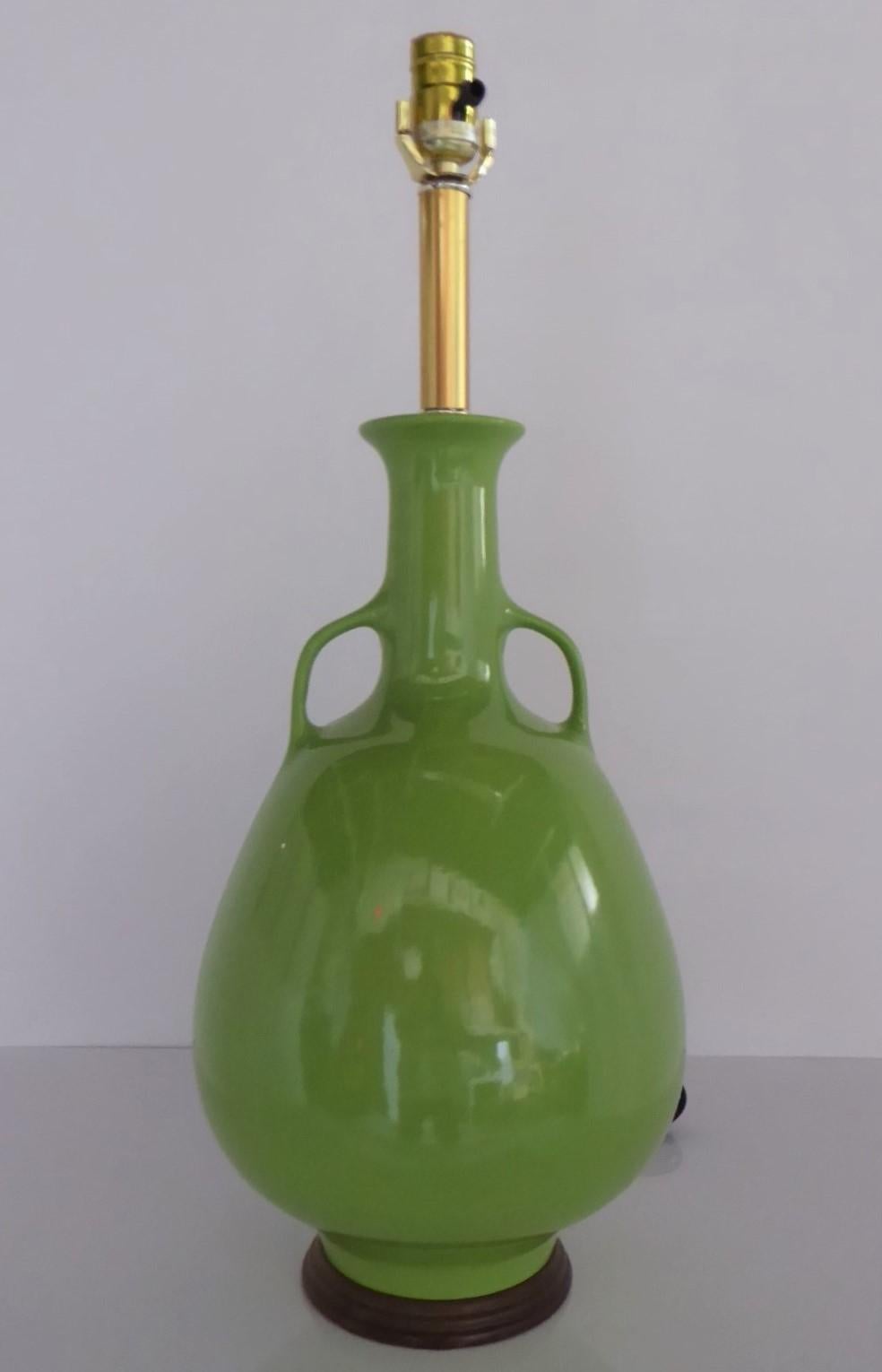 Mid-Century Modern green ceramic table lamp with an amphora shaped body and handles or arms at both sides of the neck. Rewired with 3-way UL socket. Beautiful vivid green color perfect in any Modern decor.
Measurements: 11 inches diameter x 24