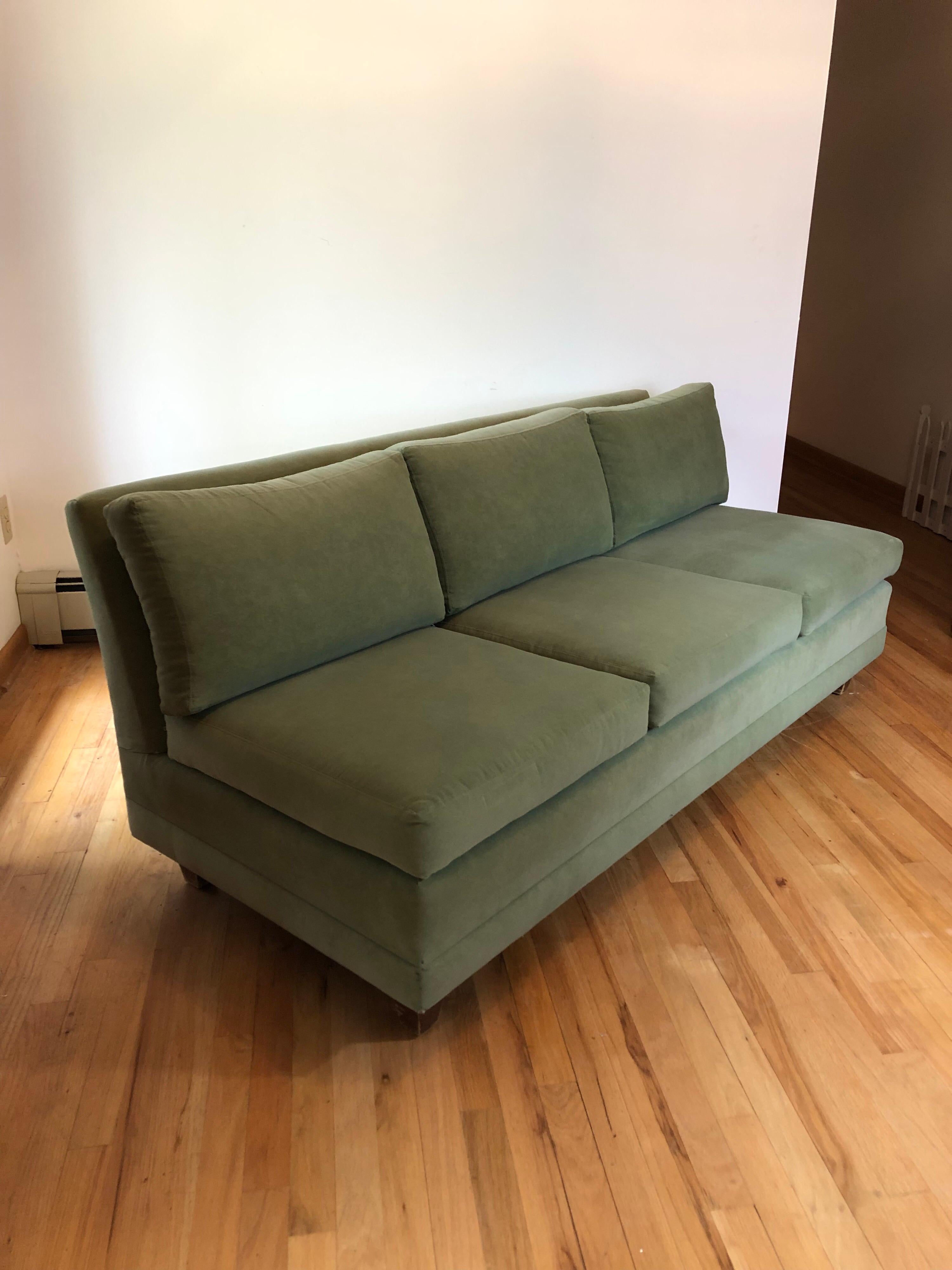 A midcentury armless slipper sofa with slight curved back. Low pile light green velvet upholstery and cushions are in excellent condition. Raised on square tapered feet. From a collection including similar seating by Knoll.