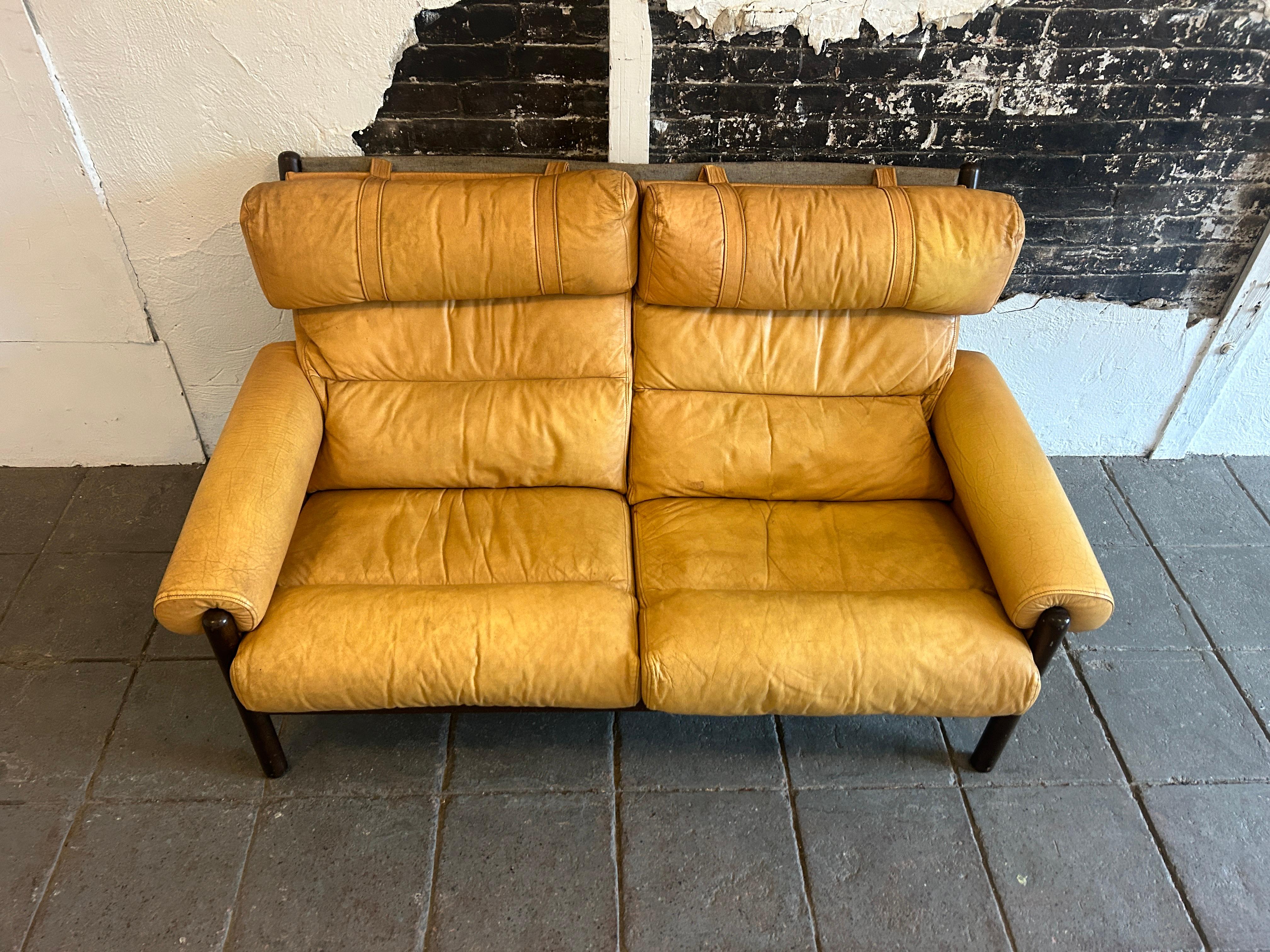 In the style of Arne Norell Safari Loveseat sofa Swedish Design

Mid-century modern teak and yellow / tan leather 2 seat small sofa. Has 2 seats with strapped pillow headrest very comfortable. Shows wear and creases to leather, wood with wear