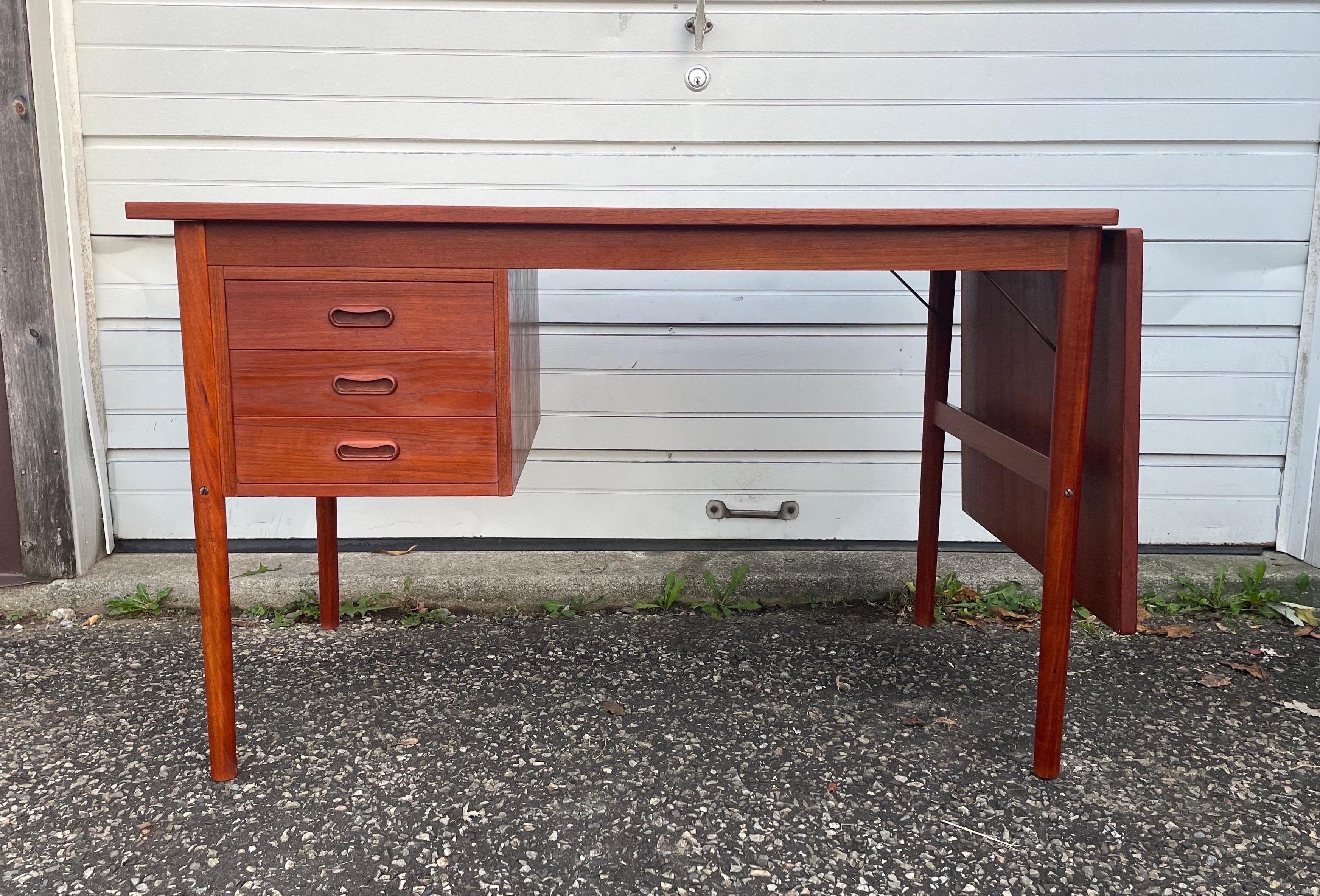 A teak desk attributed to Arne Vodder for H. Sigh & Sons. Featuring 3 drawers and a drop leaf that can be easily lifted into place to expand the desktop’s workspace.

25 3/8” D x 28 3/8” H

With the drop leaf folded down, the desk measures 46