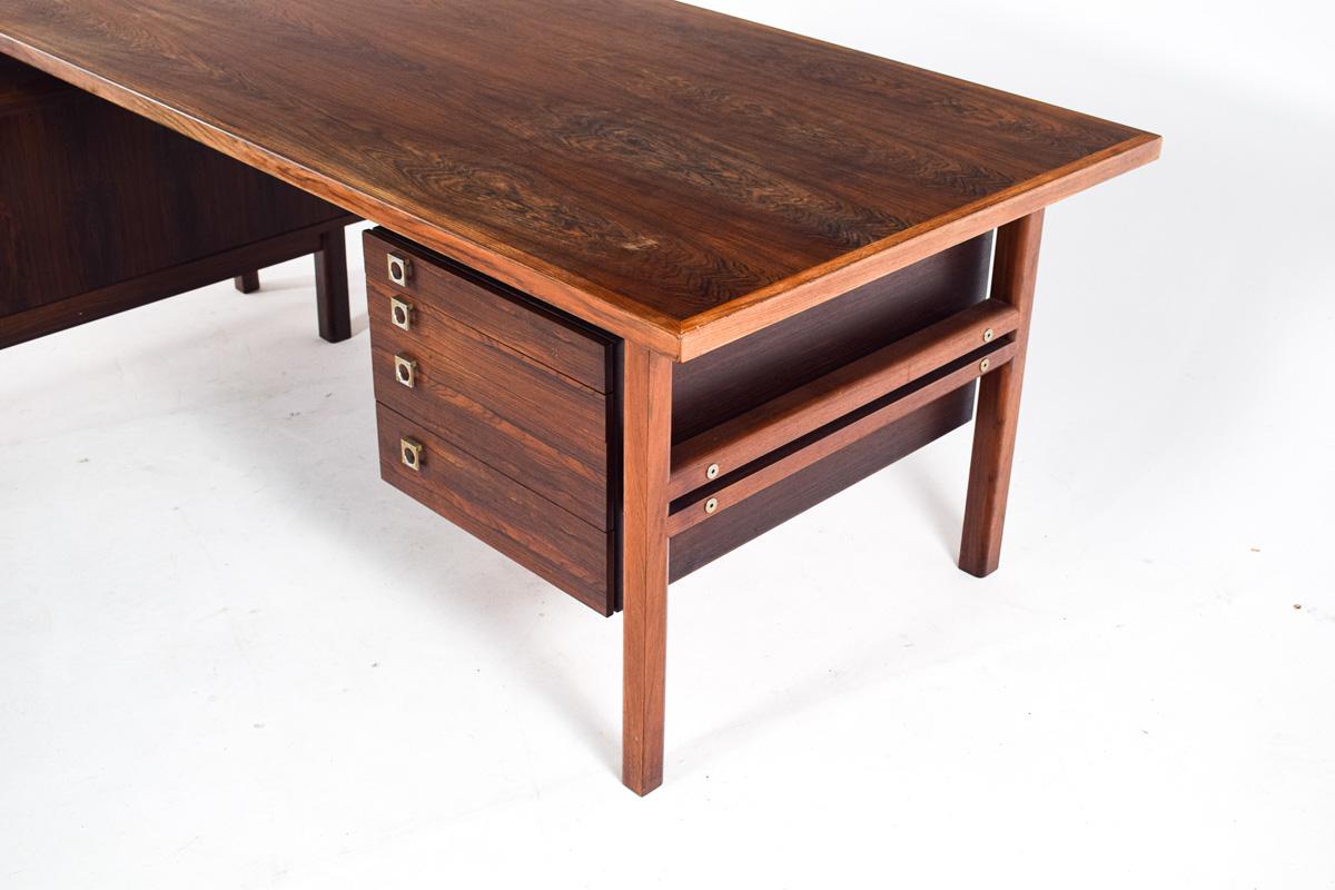 Mid Century Rosewood desk designed by Arne Vodder, showcasing the elegance and functionalism that are hallmarks of his work. The desk is a substantial piece, featuring a spacious tabletop that provides ample room for working, along with a visually