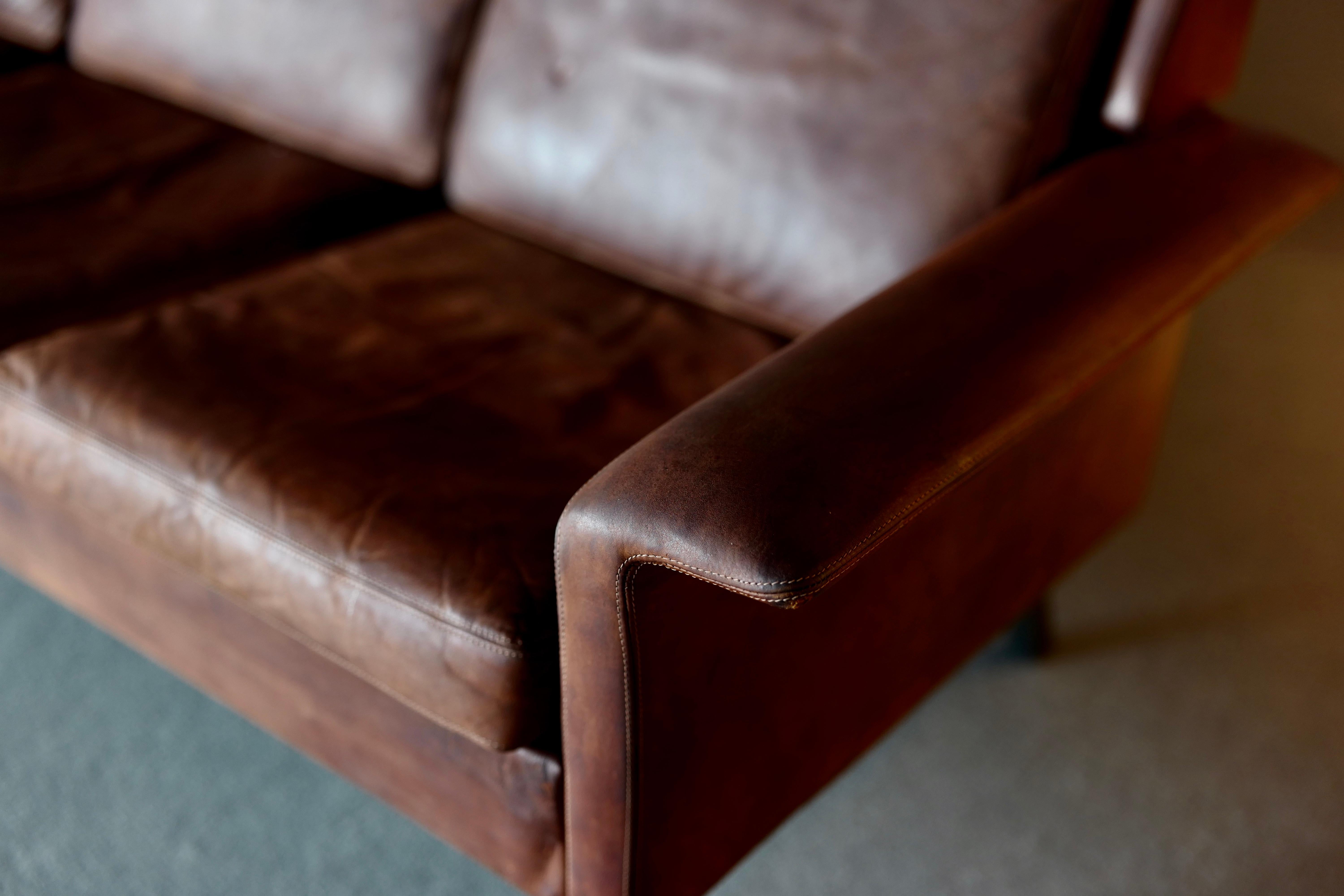 Rare sofa, a collaboration between one of the greatest Danish designers Arne Vodder and the best manufacturers Fritz Hansen. It is upholstered in well patinated cognac colored leather and has steel legs. The label remains, circa 1968.
 
 
    