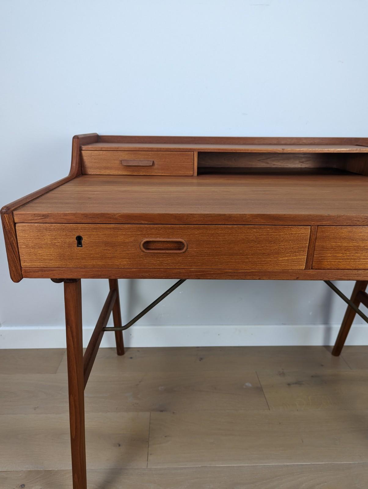 A stunning mid-century Arne Wahl Iversen desk Model 56 for Vinde Møbelfabrik, Denmark.

Made out of Teak with brass leg supports.

This two-tiered desk features splayed legs with supporting brass crossbars. It had three drawers and an organised