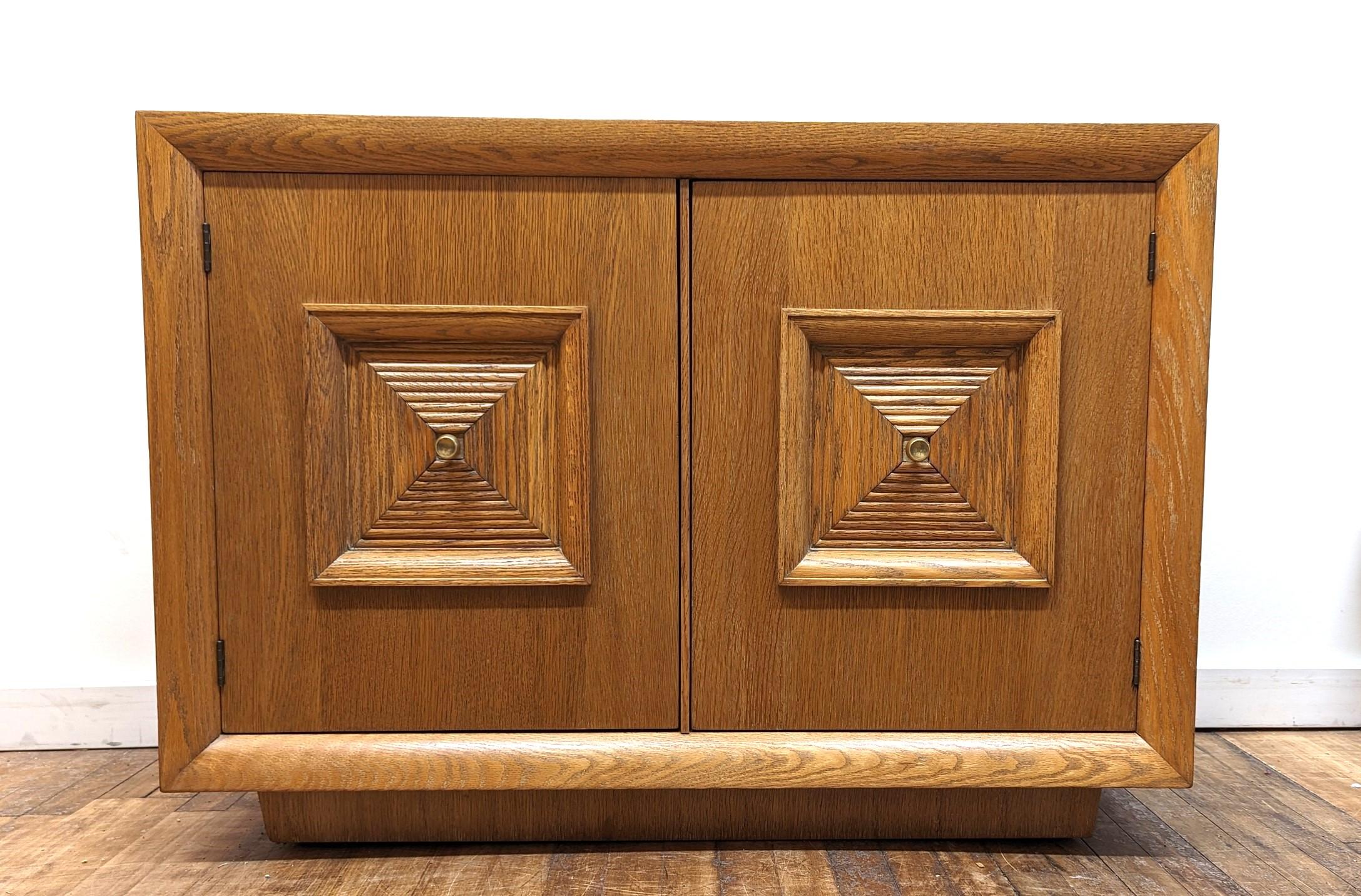 Art Deco Mid Century Oak Credenza Sideboard in the style of Maxime Old.  Quality made small Credenza of cerused Oak with squared dimensional door medallions and solid brass pulls.  Raised on a plinth bass having inset spring ball latches that hold