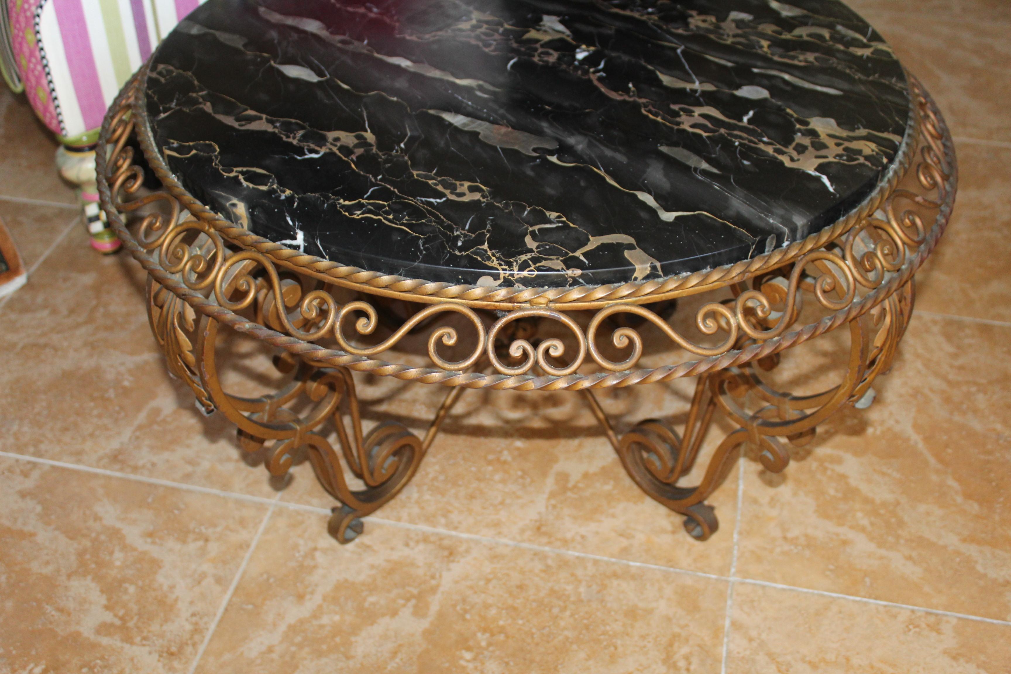 Table basse ronde en fer forgé de style Art Déco par le Designer (Gilbert Poillerat ) avec une finition peinte en or et un plateau en marbre italien (noir et or).  Le diamètre extérieur de la table est de 32 pouces et le diamètre du marbre est de
