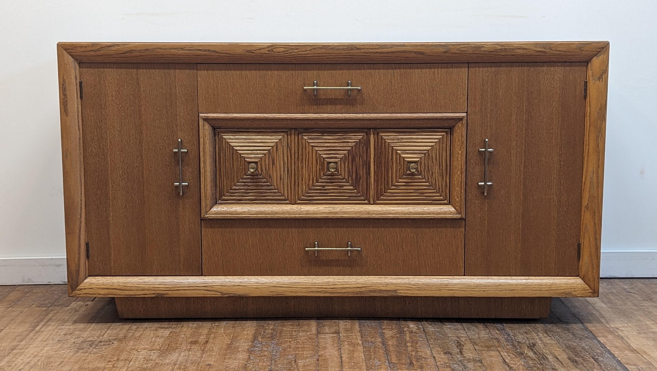 Mid Century Art Deco Credenza Sideboard after Maxime Old.  Cerused Oak Credenza Sideboard French Art Deco style after Maxime Old. Quality made Credenza of Cerused Oak with squared dimensional door medallions and solid brass pulls. Raised on a plinth