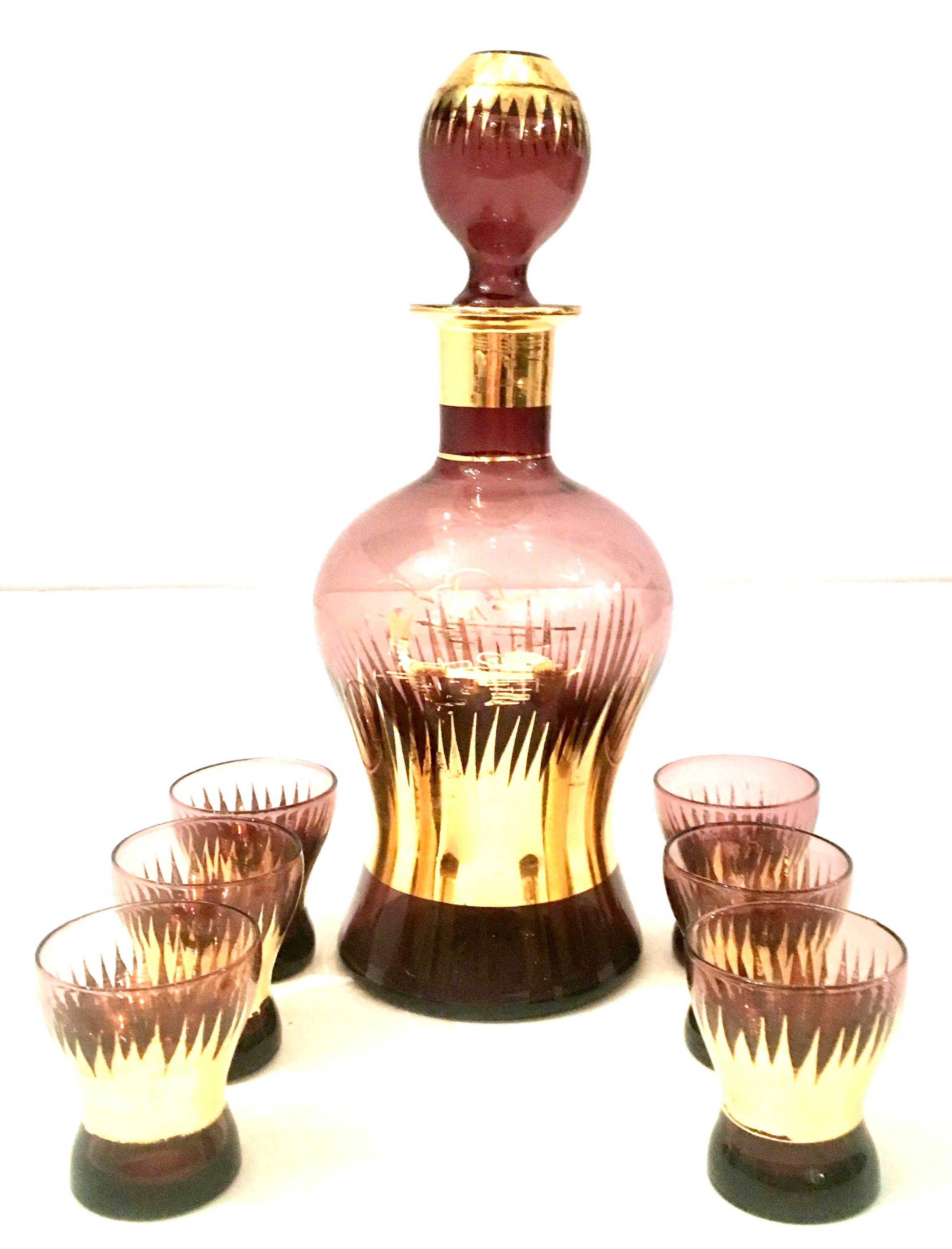 Mid-Century Art Deco Bohemia Amethyst Blown Art Glass & 22-karat gold seven piece drinks set. The decanter features a central 22-karat gold water and boat motif.
Set includes one decanter with stopper and six glasses.
Glasses measure, 2