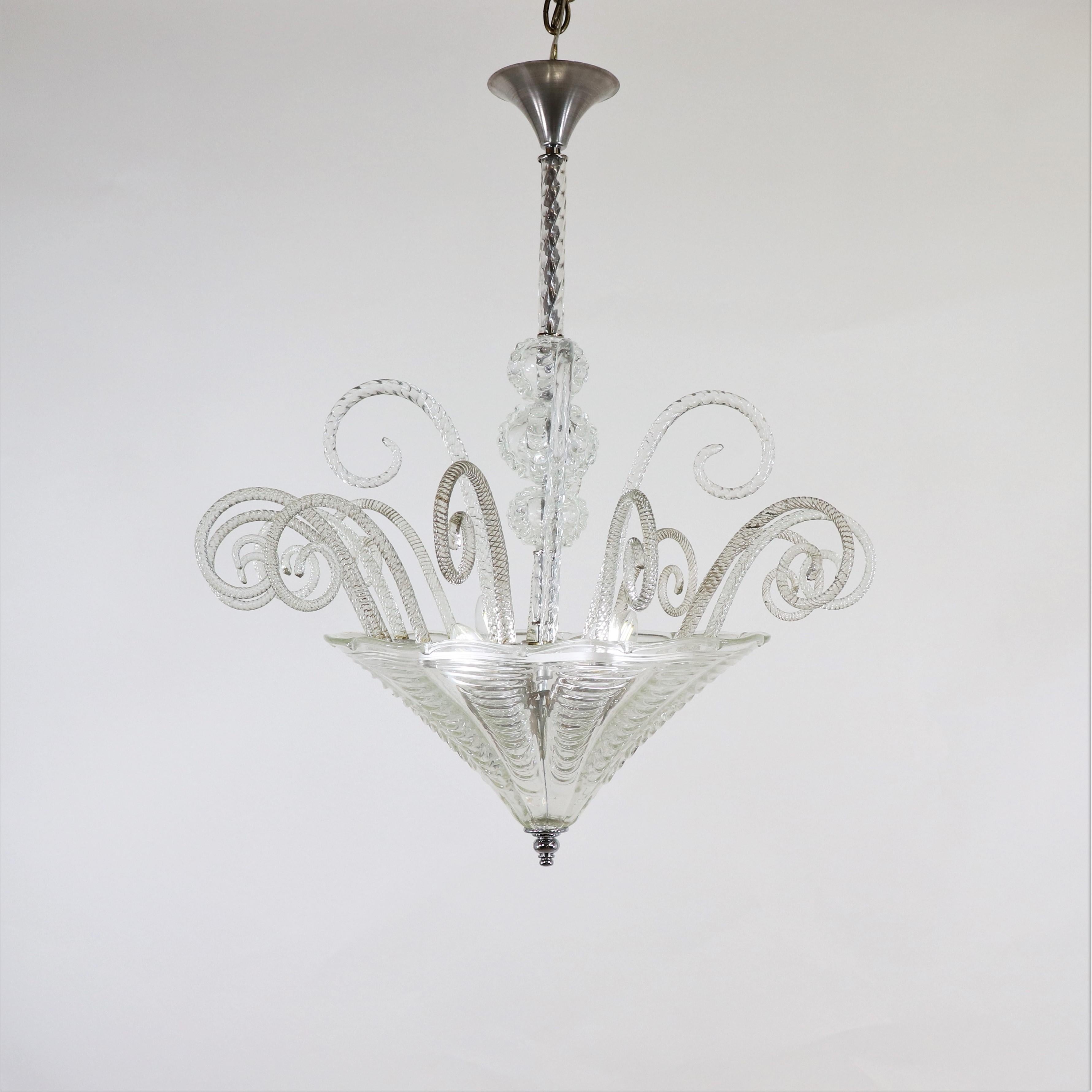 Découvrez la grandeur historique de cette suspension Murano de style art-déco en cristallo, caractérisée par de longues décorations en spirale rappelant des fougères enroulées émanant de la large vasque centrale en forme de cône. La pièce se