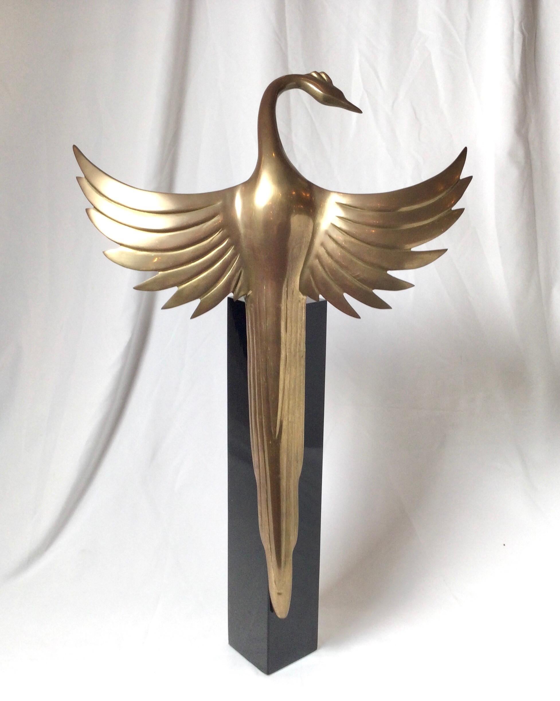 Art Deco styled brass bird sculpture with black enameled metal base. The tall square base with bird resting with wings expanded.
