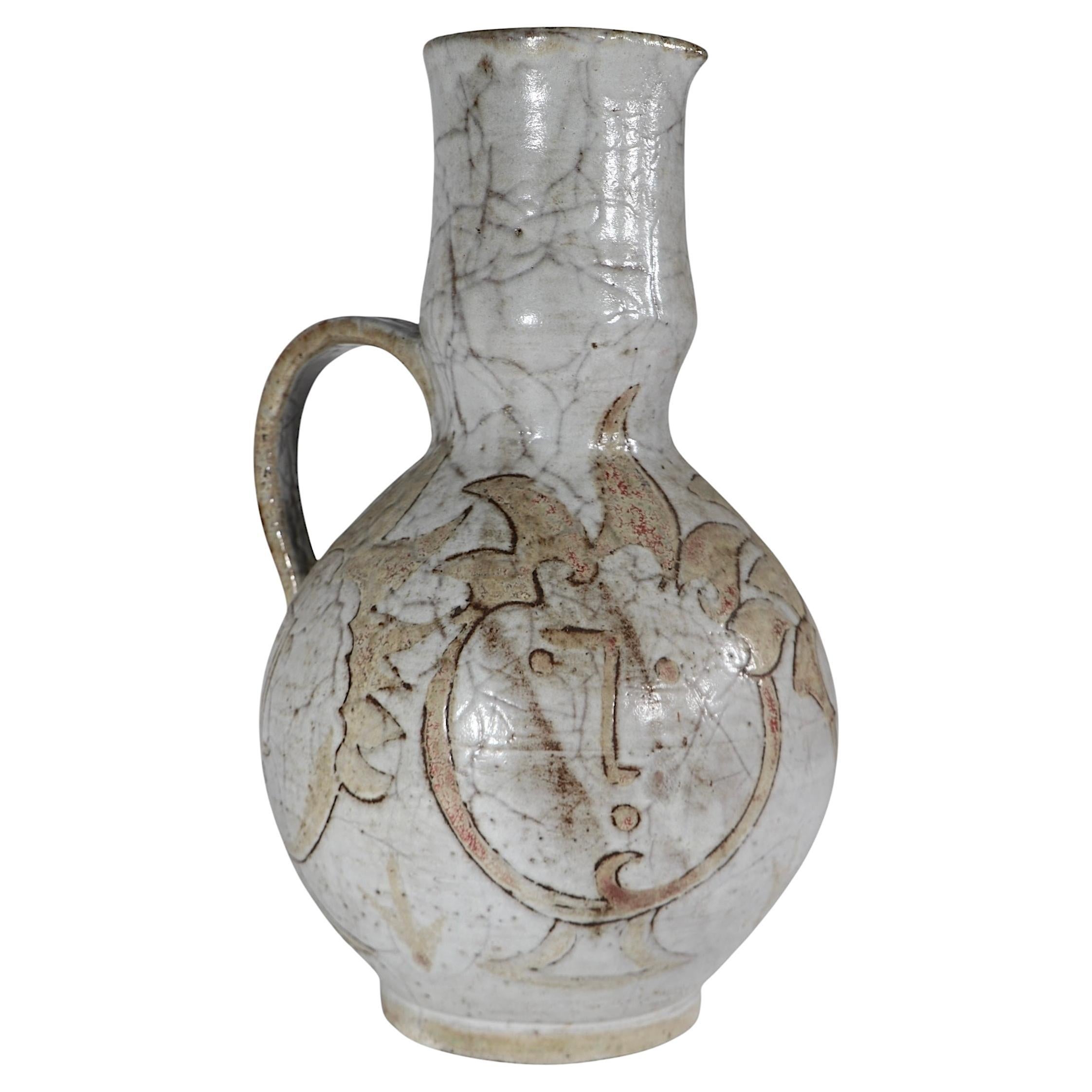 Exceptionnelle aiguière en poterie d'art du célèbre céramiste français Max Boissaud. Cet exemple inhabituel présente trois visages stylisés sur le corps bulbeux, exécuté sur un fond de couleur terre. Le vase est en excellent état, original, propre