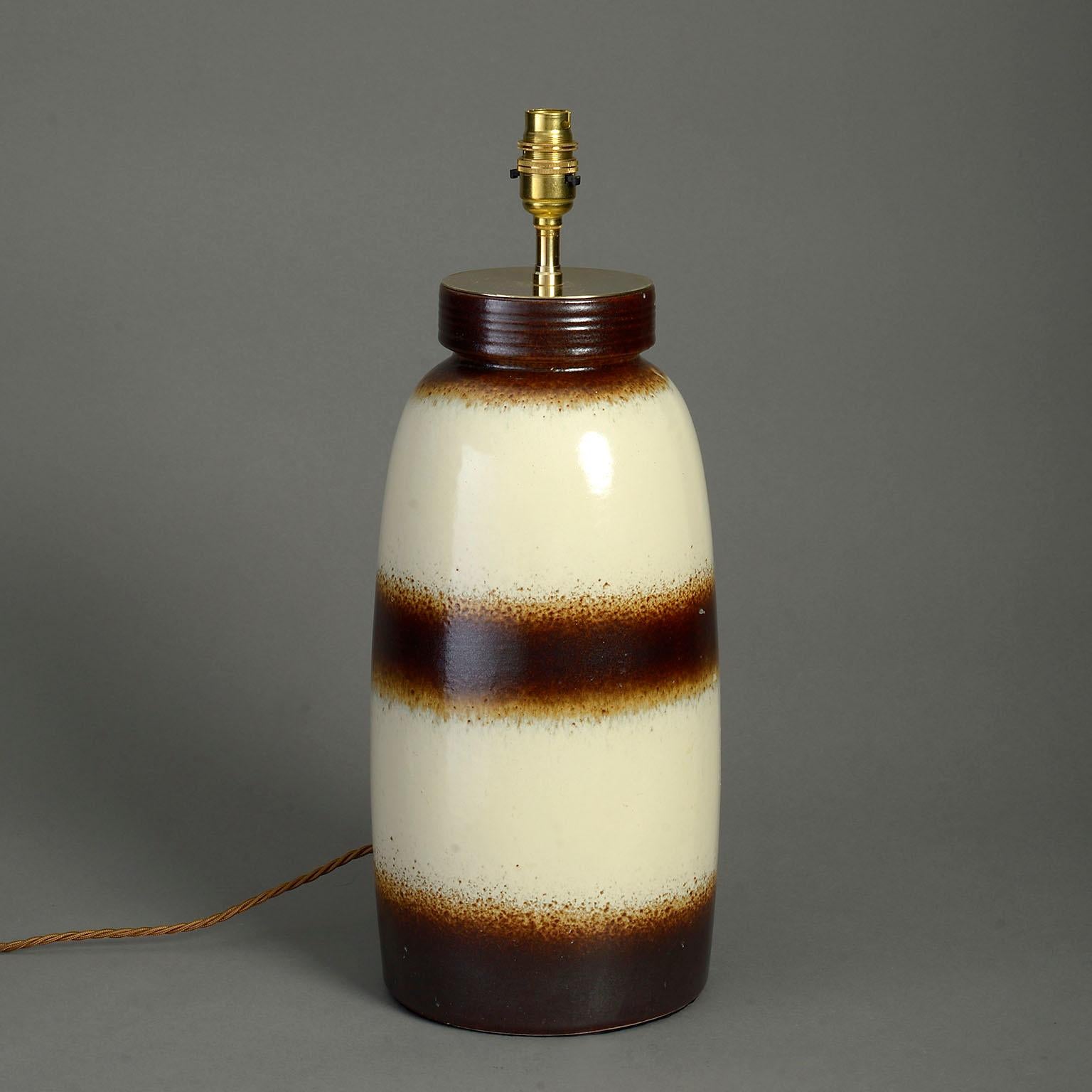 A mid-twentieth century pottery art vase lamp, the body with chocolate glazed bands upon a cream ground.

Dimensions refer to ceramic elements only.

Wired to UK standards. Can be rewired to all International specifications inclusive.

Shade