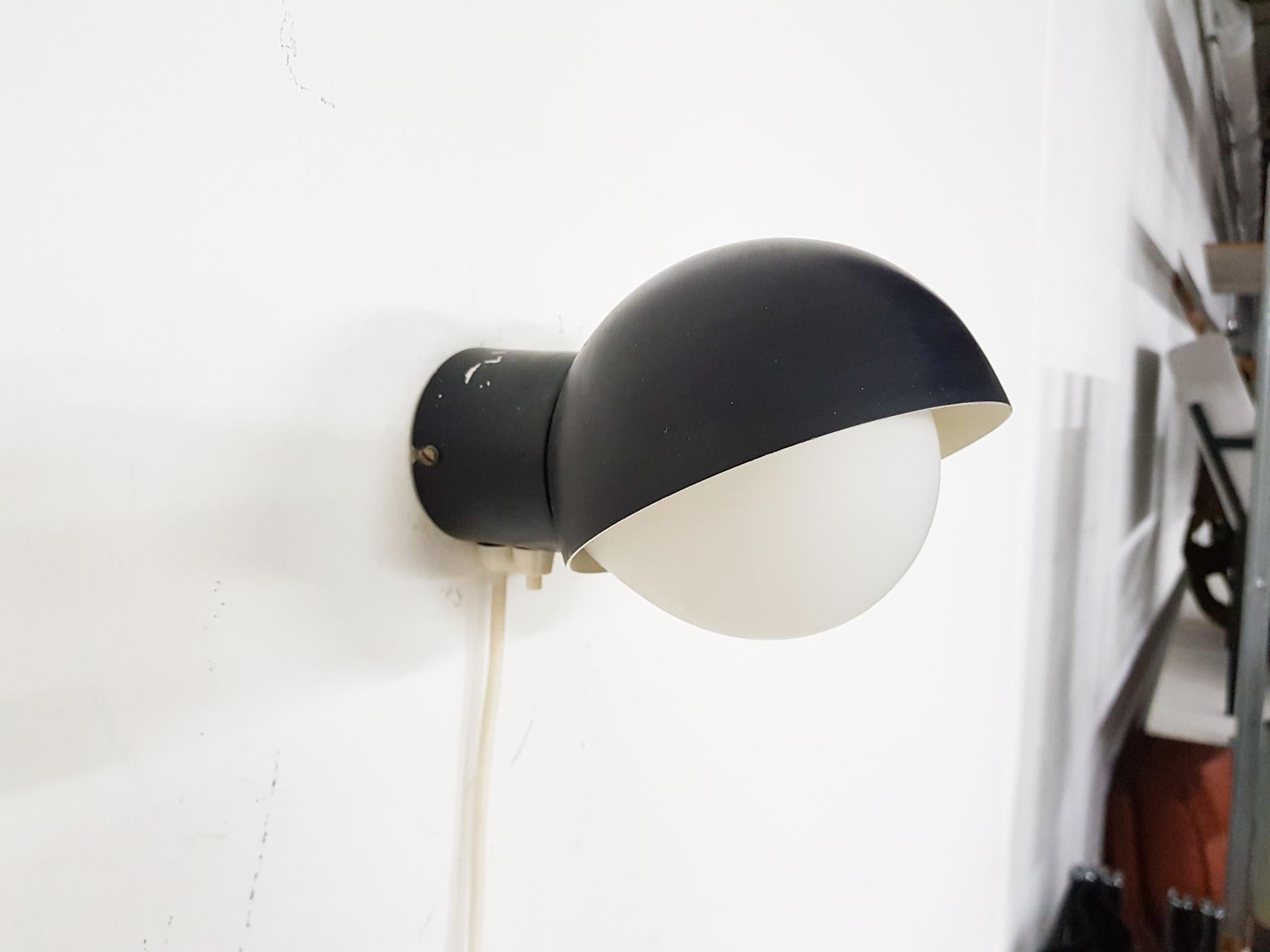 Black metal wall light with milk glass lamp shade.