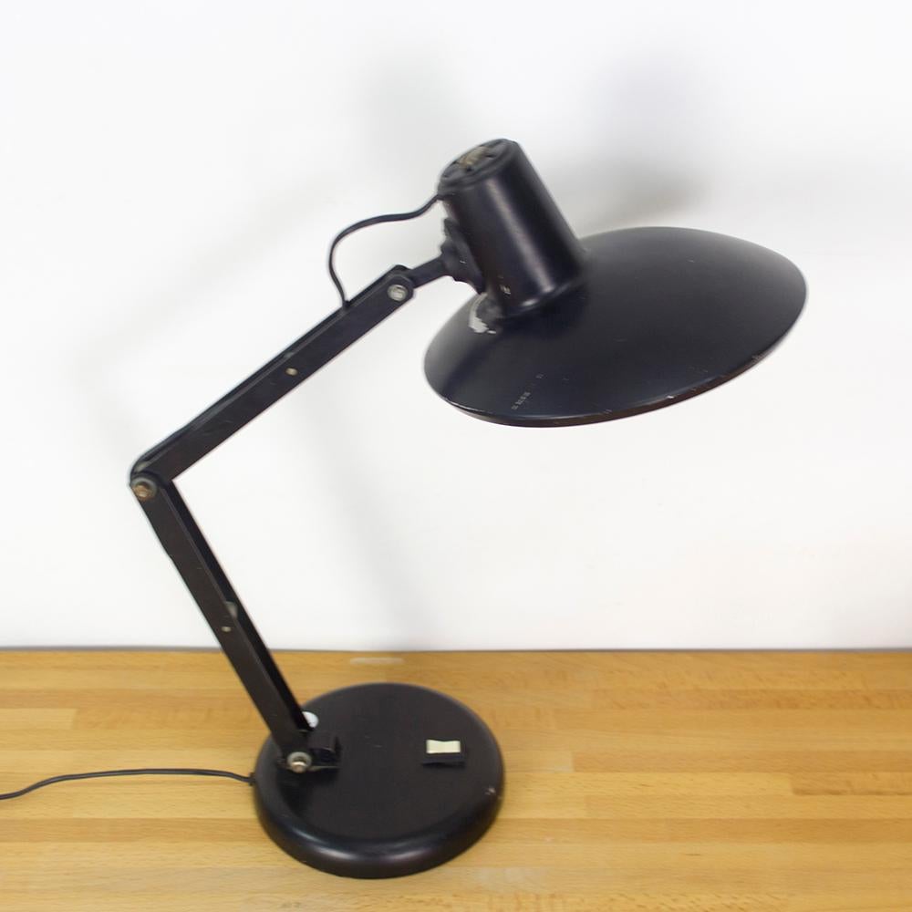 Midcentury desk light with articulated arms and an asymmetric lamp shade.
This lamp was manufactured in Spain in the 1960s and is made of black colored metal.
Elegant shape and color that would fit well in any style of decoration.