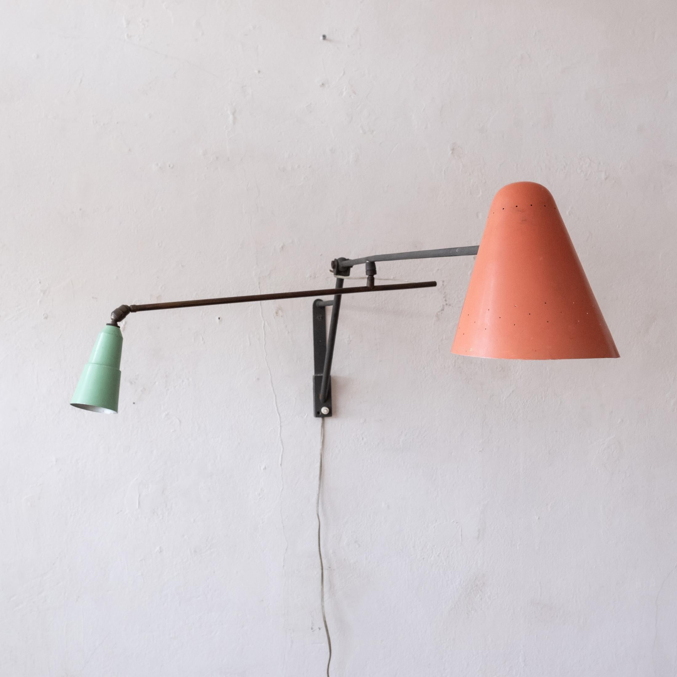 Articulating wall mounted lamp of European origin. Both arms move up and down and rotate. The shades are adjustable as well. A real architectural piece of mid century modern design. 1950s 