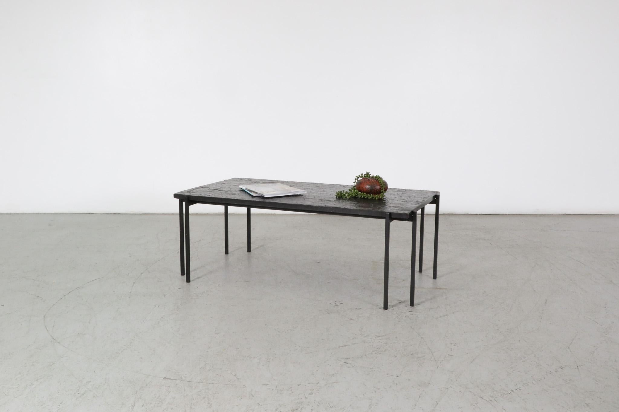 Mid-Century, 1960's, Dutch coffee table featuring a black stone top and a brutalist, black enameled metal base. The table has a strikingly architectural design with attractively split legs on each corner. It is in original condition with some