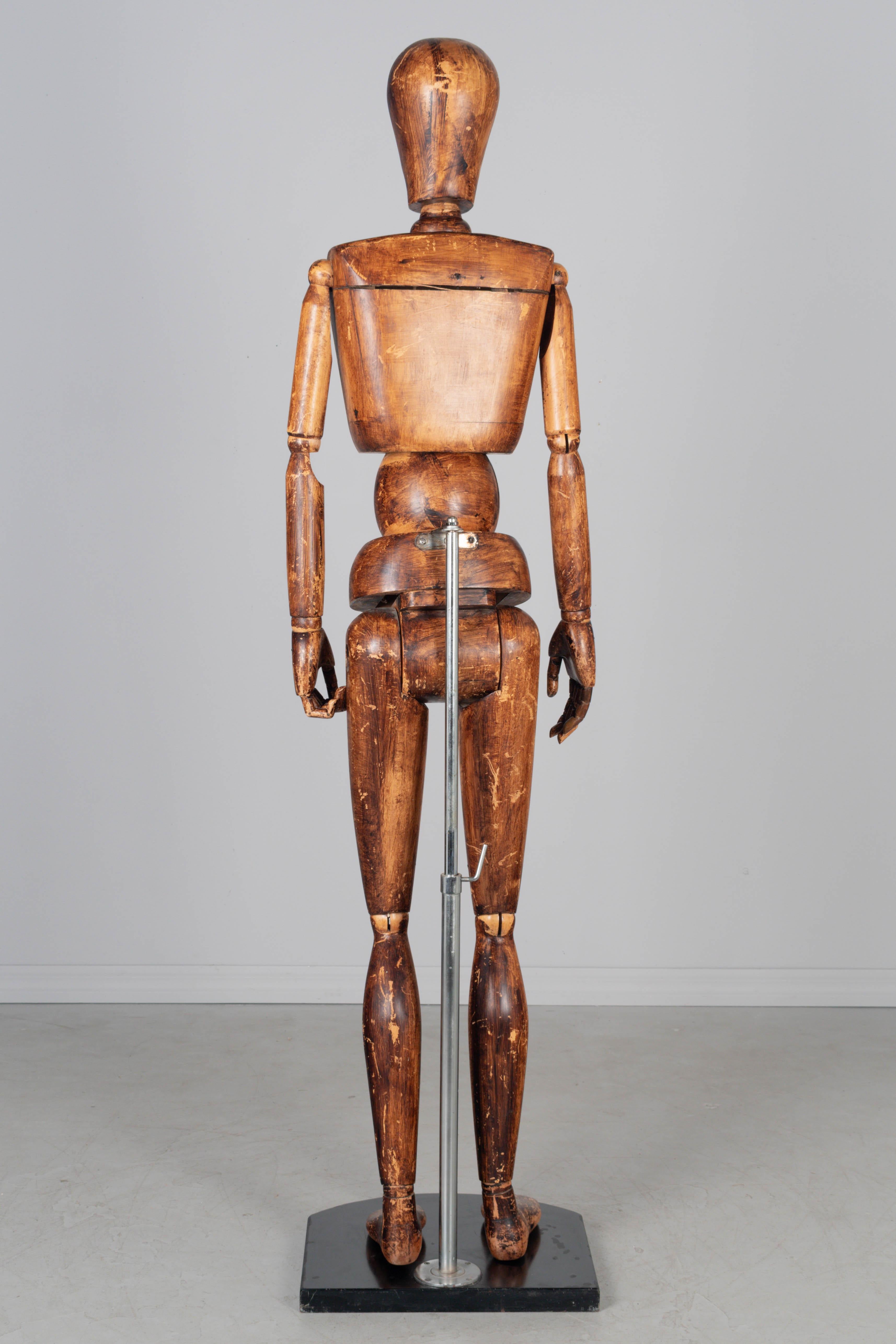 Maniquí o modelo articulado de artista italiano de mediados de siglo, de madera maciza patinada y teñida. La figura se sujeta a una barra metálica fijada a una pesada base negra. Puede colocarse en varias posturas o retirarse del soporte y colocarse